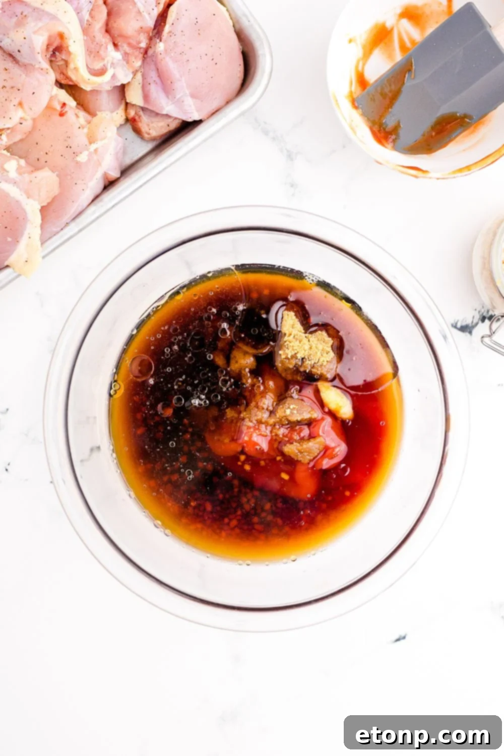 Mixing the Huli Huli Chicken marinade in a bowl with raw chicken waiting nearby to be added