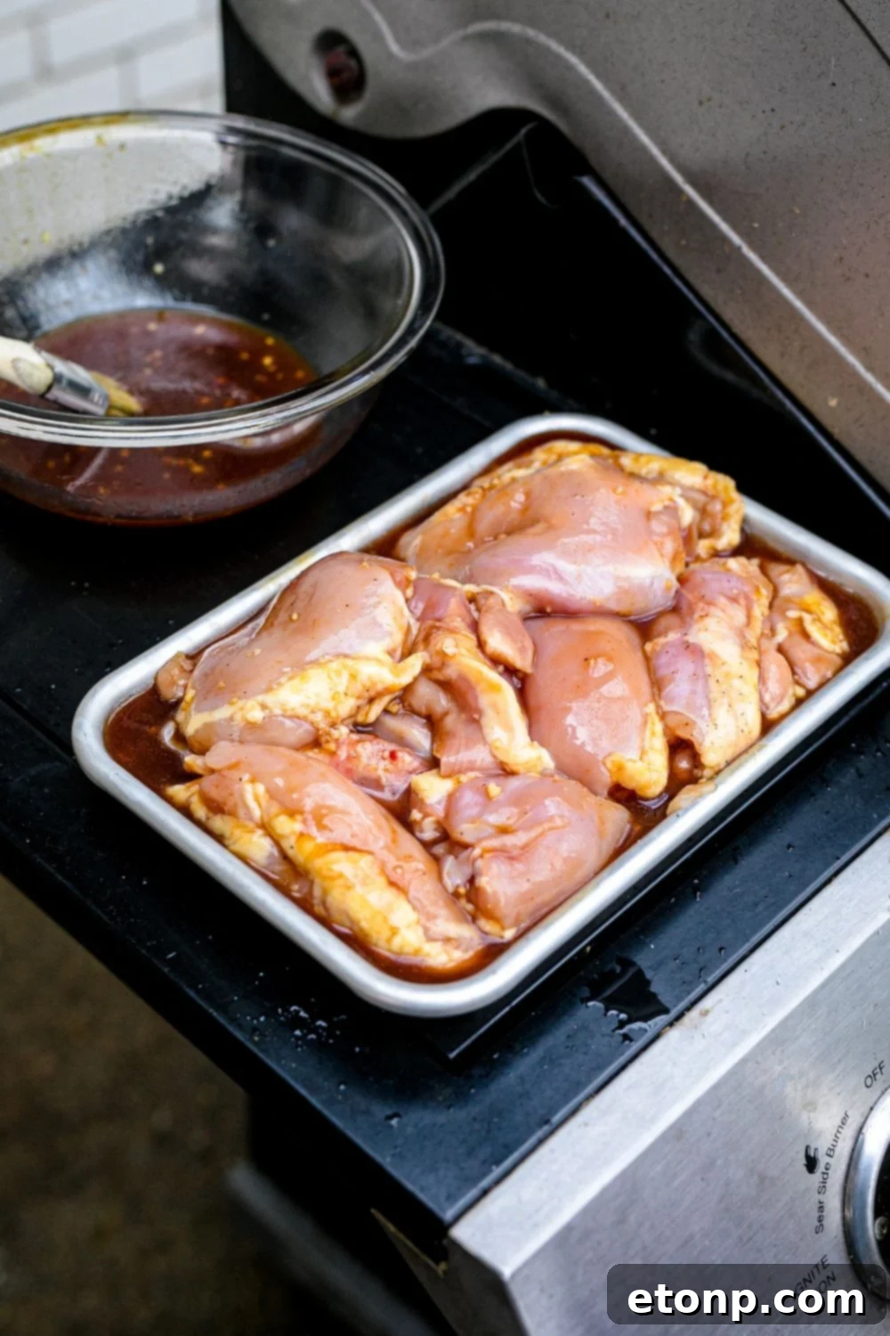 Marinated Huli Huli chicken placed in a pan on the grill, ready for cooking