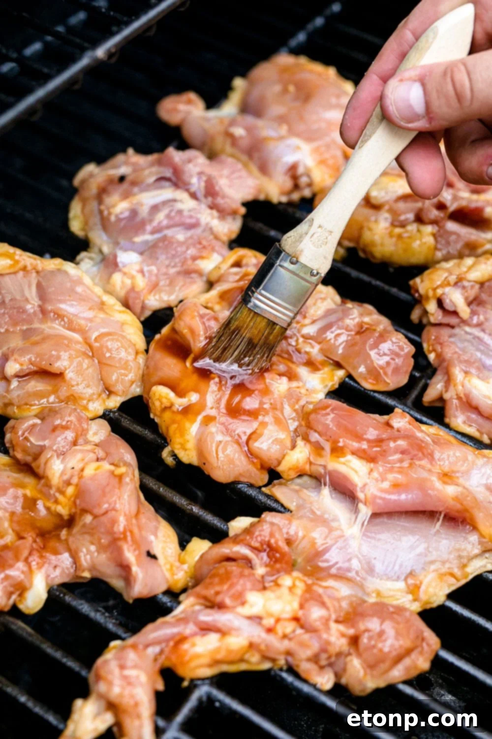 Huli Huli Chicken being skillfully basted with the flavorful sauce while grilling, enhancing its caramelization
