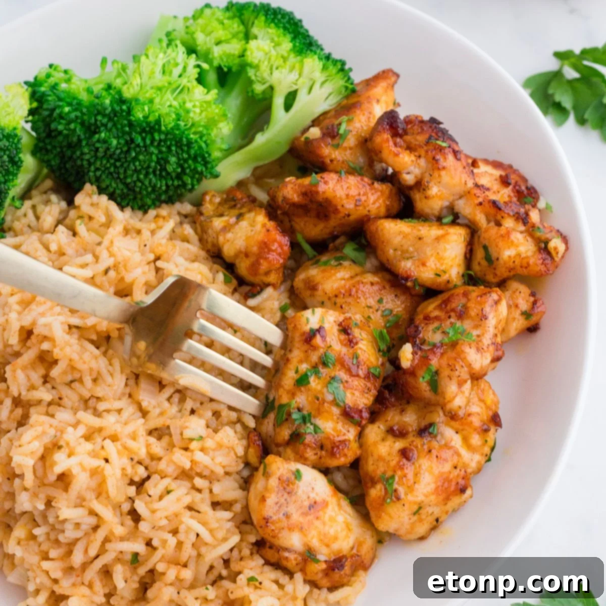 Buttery Garlic Chicken Bites 2 Garlic Butter Chicken Bites on plate with rice and broccoli on side of it