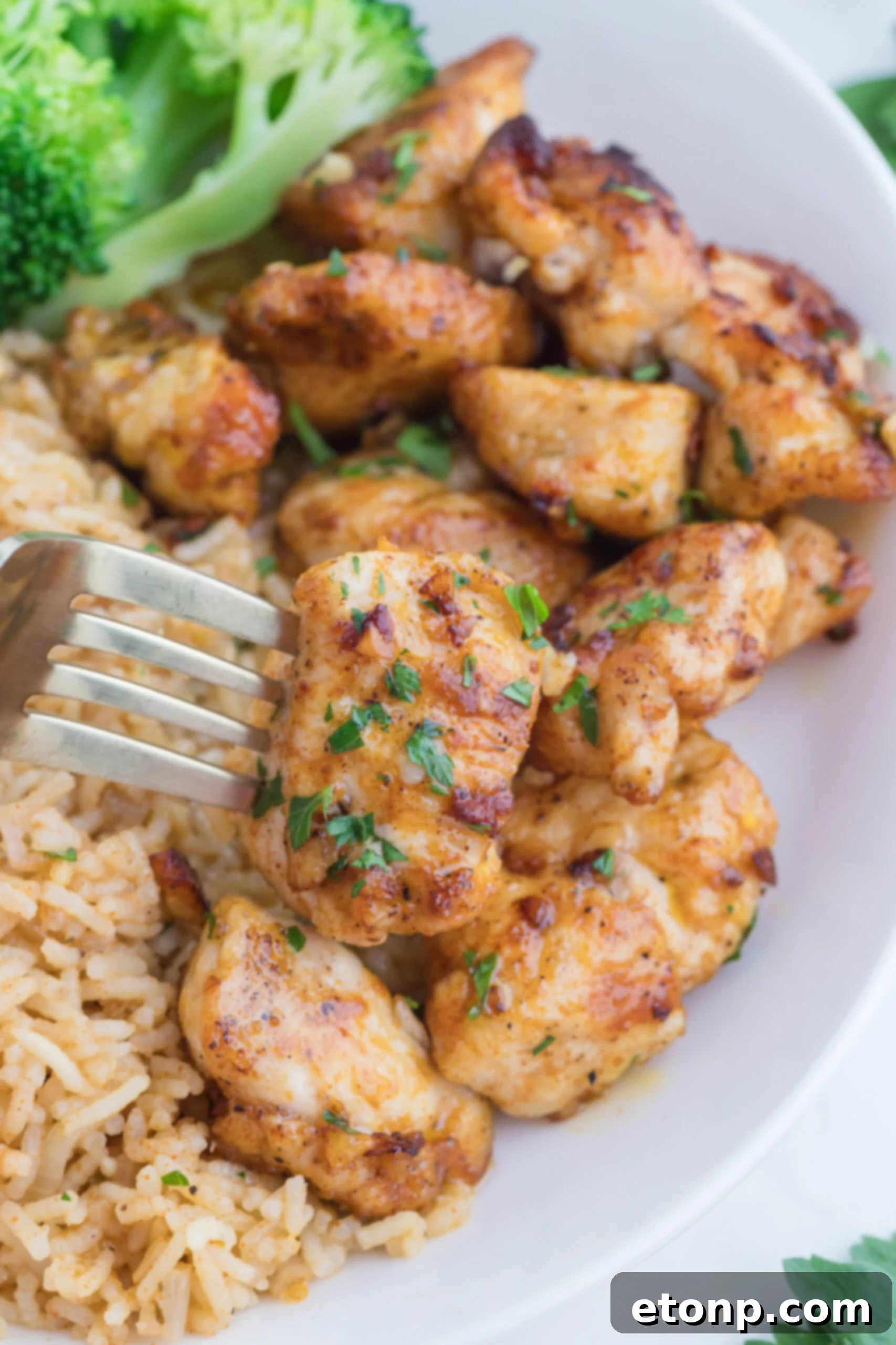 Buttery Garlic Chicken Bites 19 Garlic Butter Chicken Bites on a white plate with a fork lifting one up