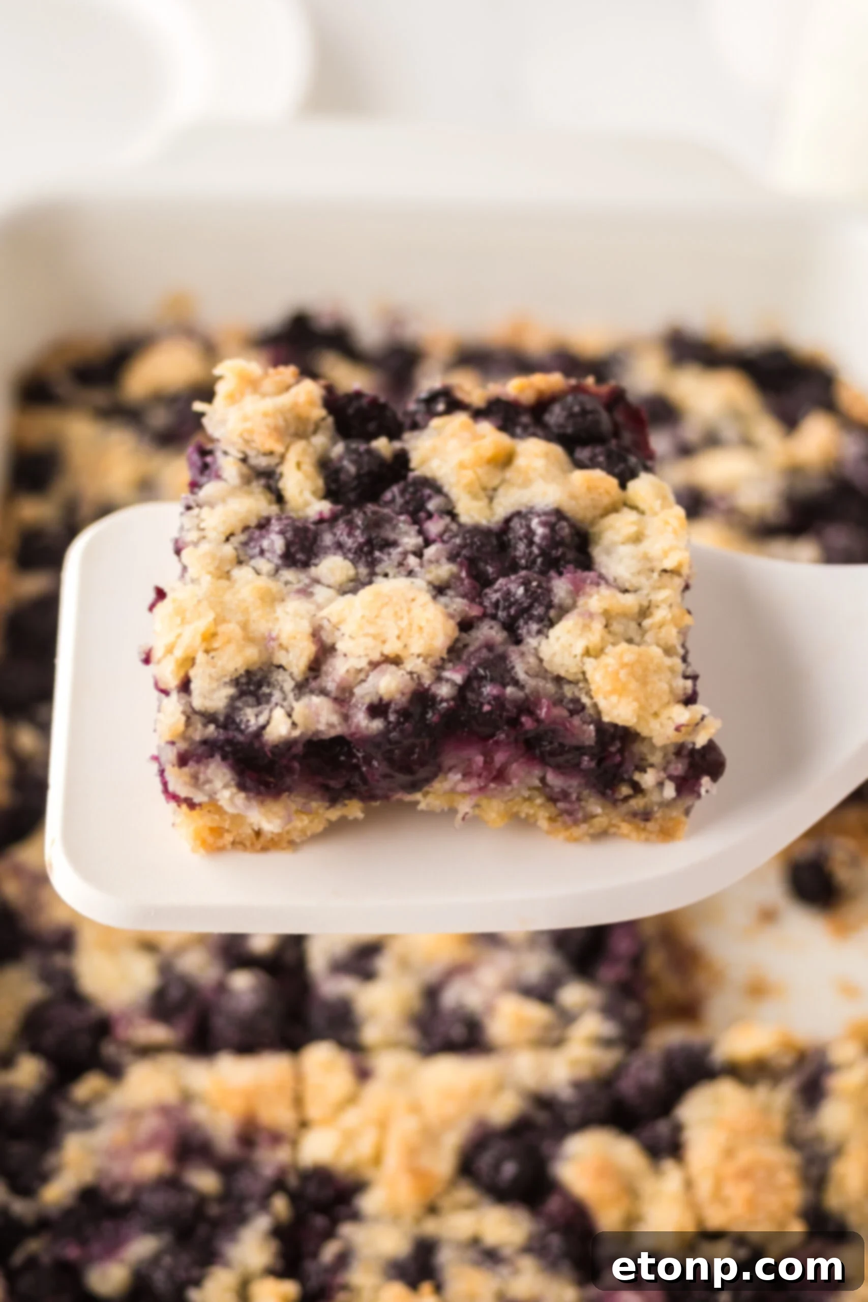 blueberry crumble bar being lifted up by a white spatula