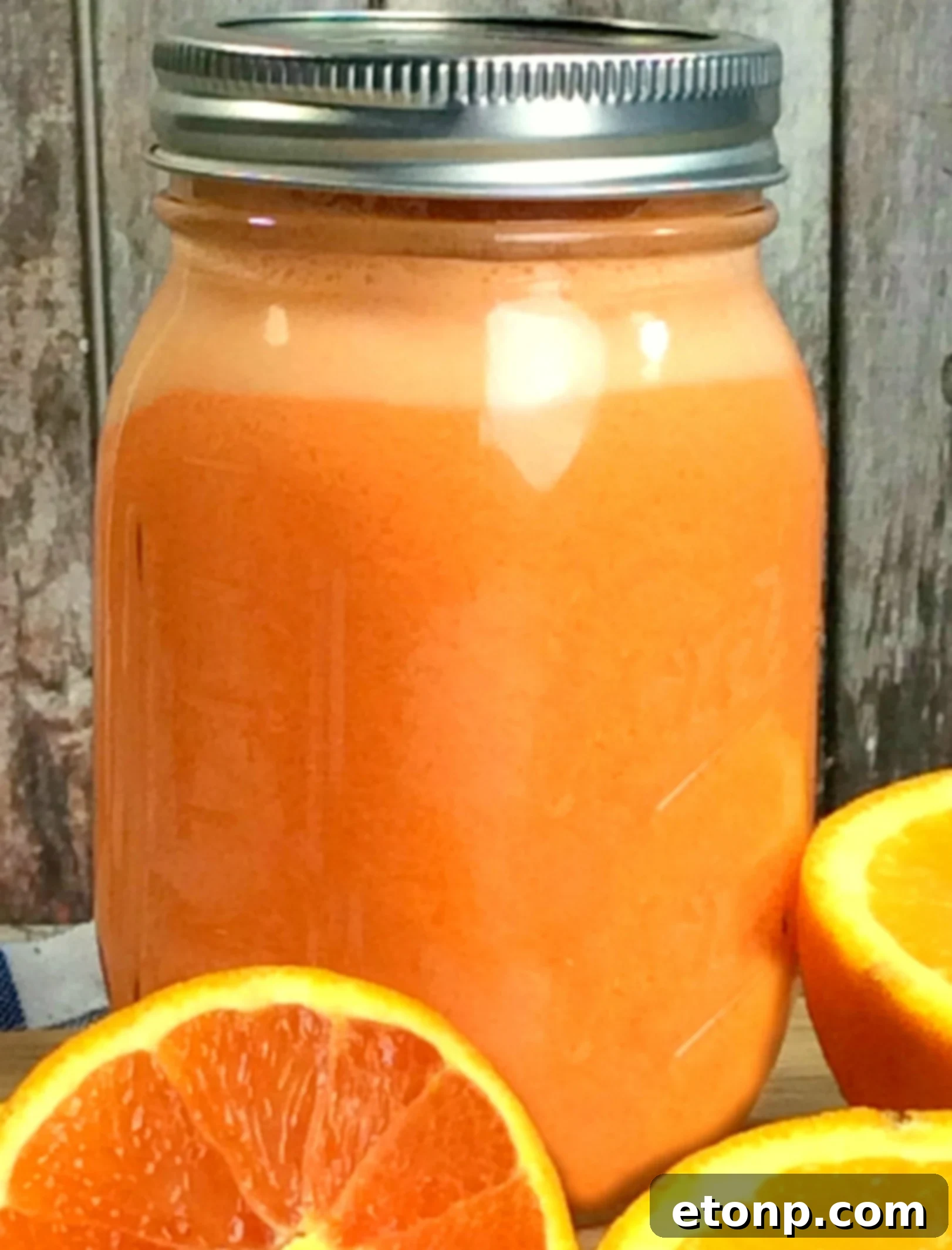 Three Mason jars filled with vibrant orange Creamsicle Moonshine, ready for chilling.
