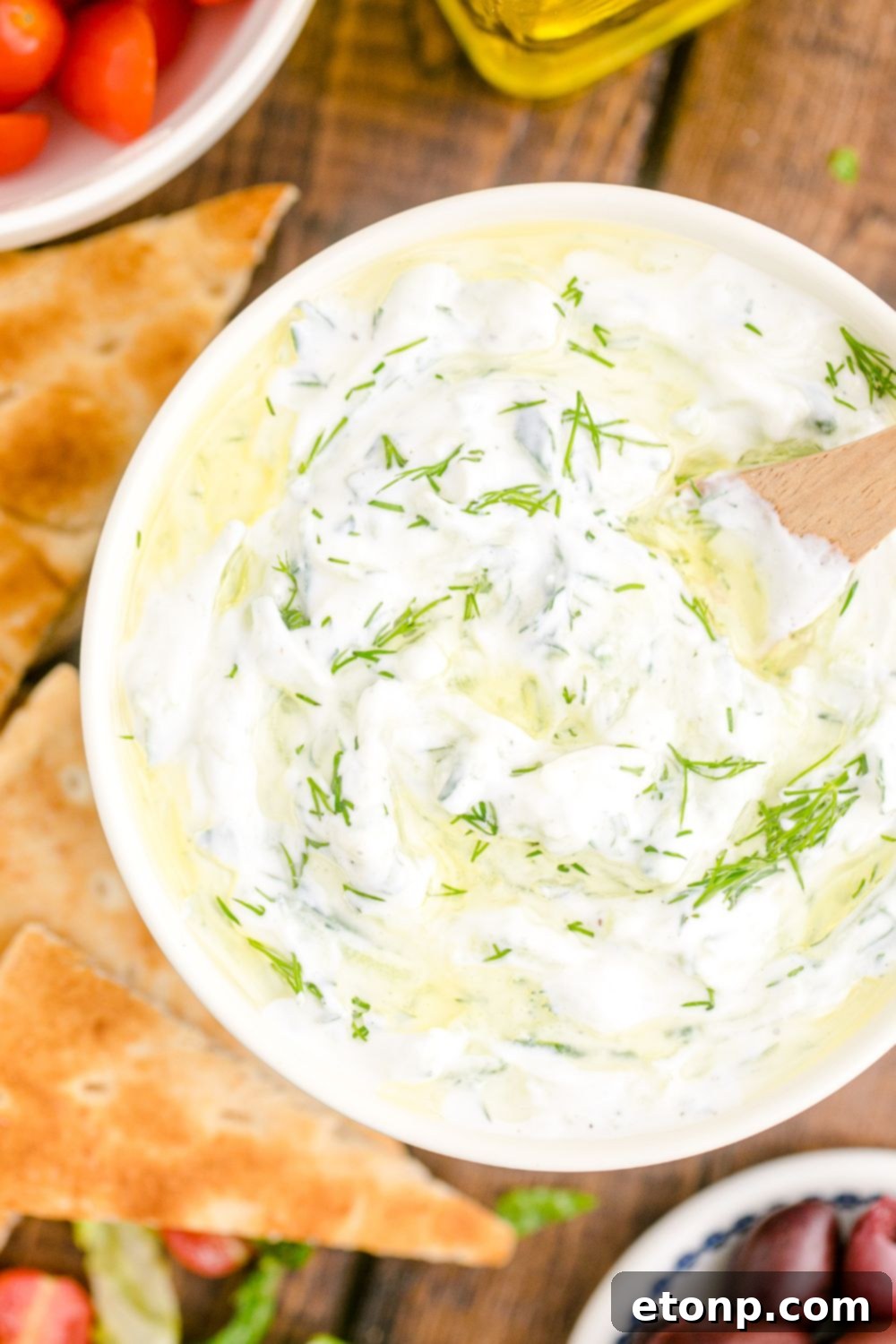 overhead look of Tzatziki Sauce in a bowl topped with fresh dill