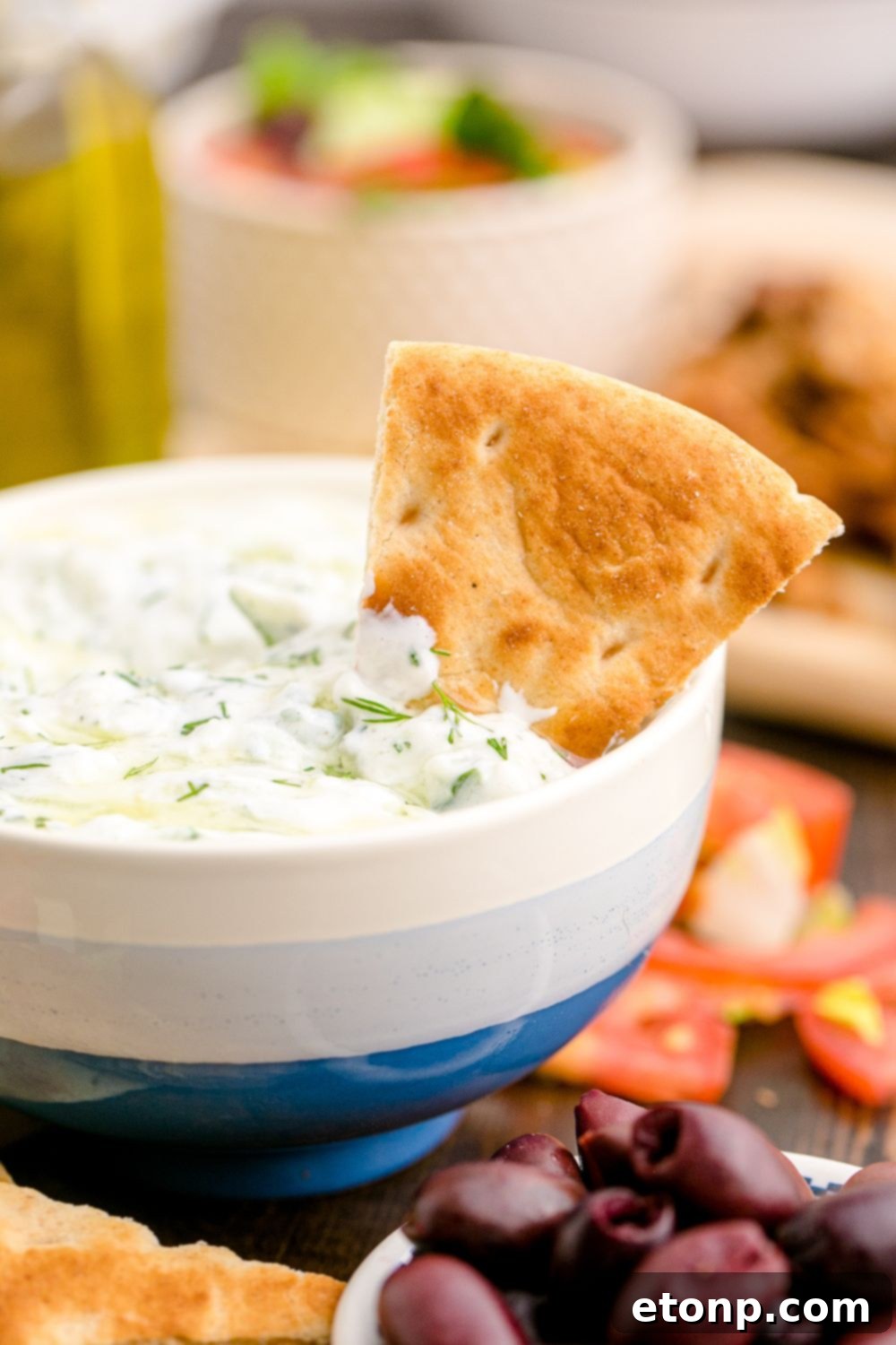 Traditional Greek tzatziki in a bowl with a pita wedge in the dip