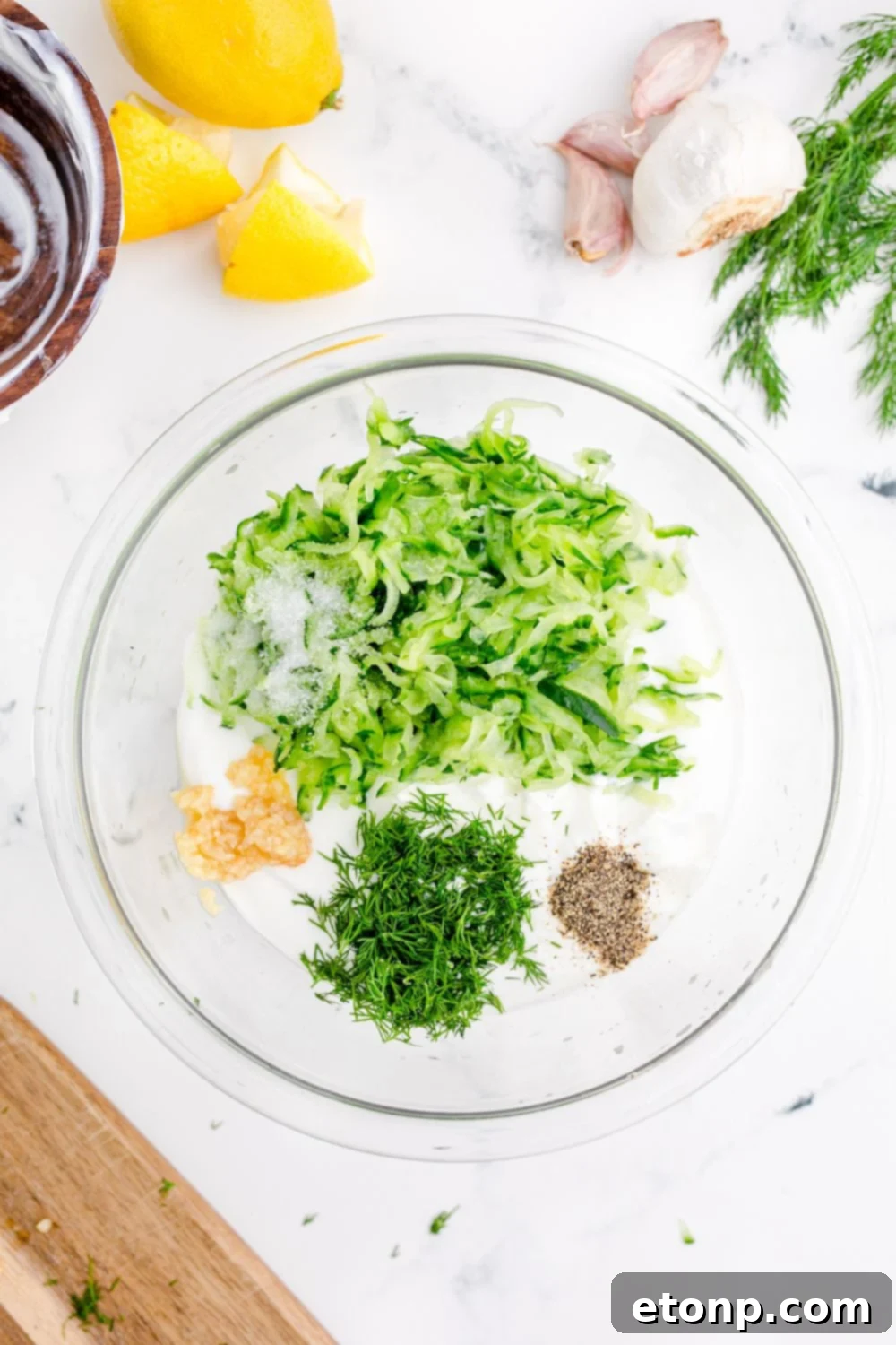 ingredients for Tzatziki Sauce in a glass bowl on table 