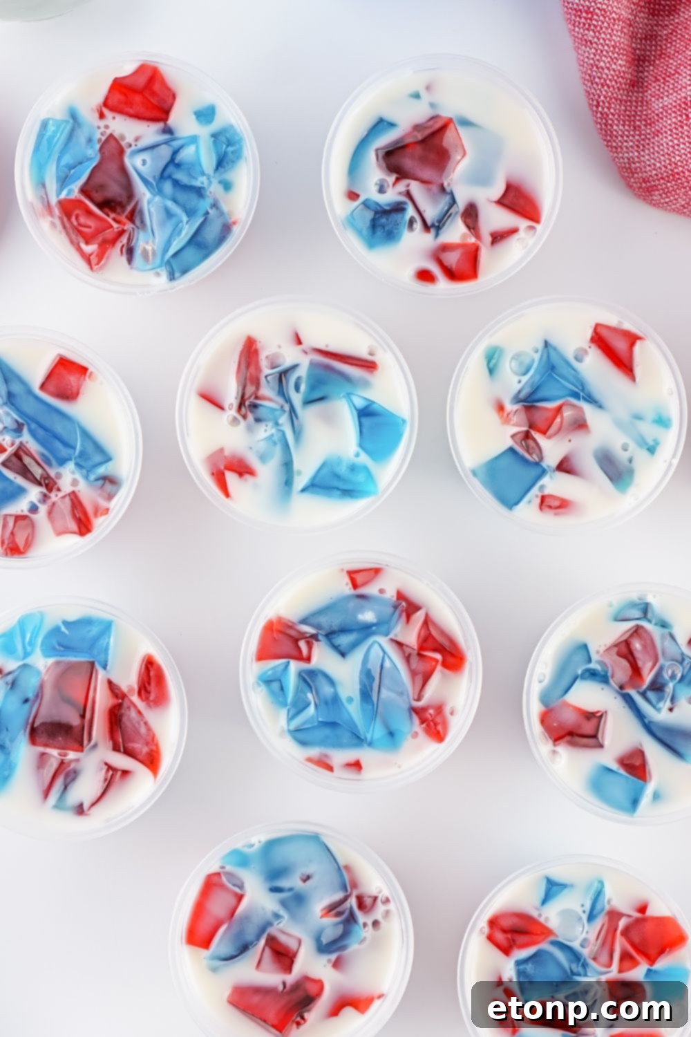 A finished batch of Red, White, and Blue Stained Glass Jello Shots arranged in their individual containers on a table, ready for chilling.