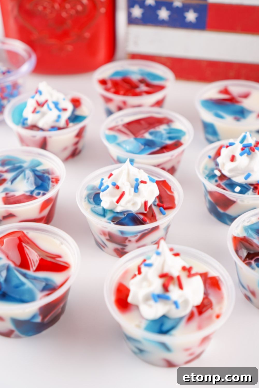 Red, White, and Blue Stained Glass Jello Shots scattered across a table in individual containers, showcasing their readiness for serving.
