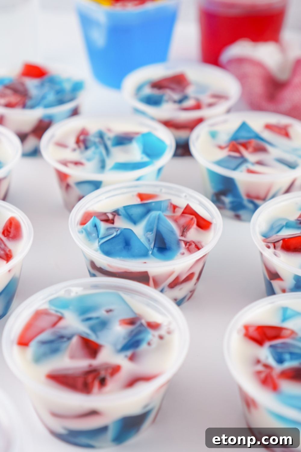 A scattered arrangement of red, white, and blue jello shots in containers on a table, showcasing their festive colors.