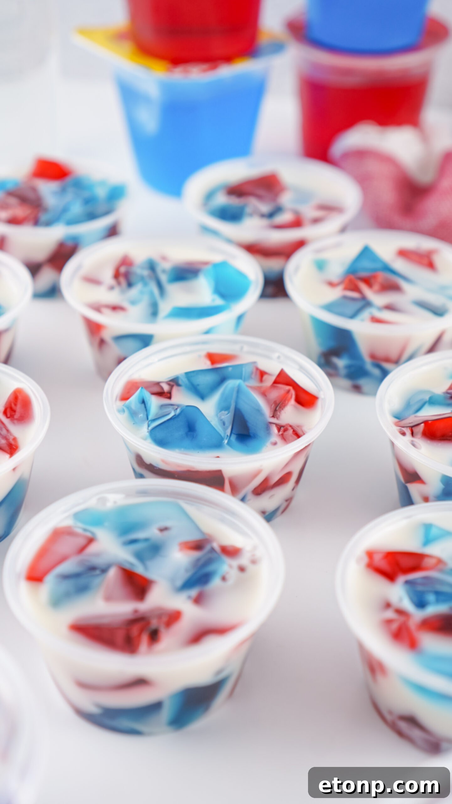 An artistic close-up of several red, white, and blue jello shots on a pristine white table, highlighting their clarity and vibrant colors.