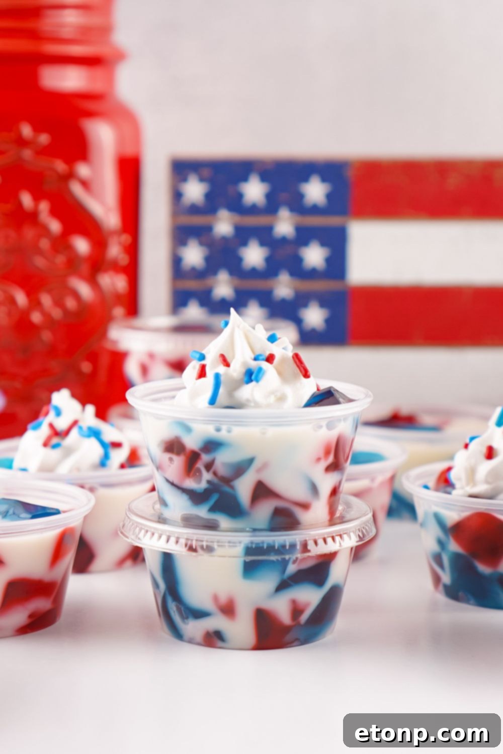 Red, White, and Blue Jello Shots in single-serve containers stacked neatly on a table, showcasing their perfect party size.