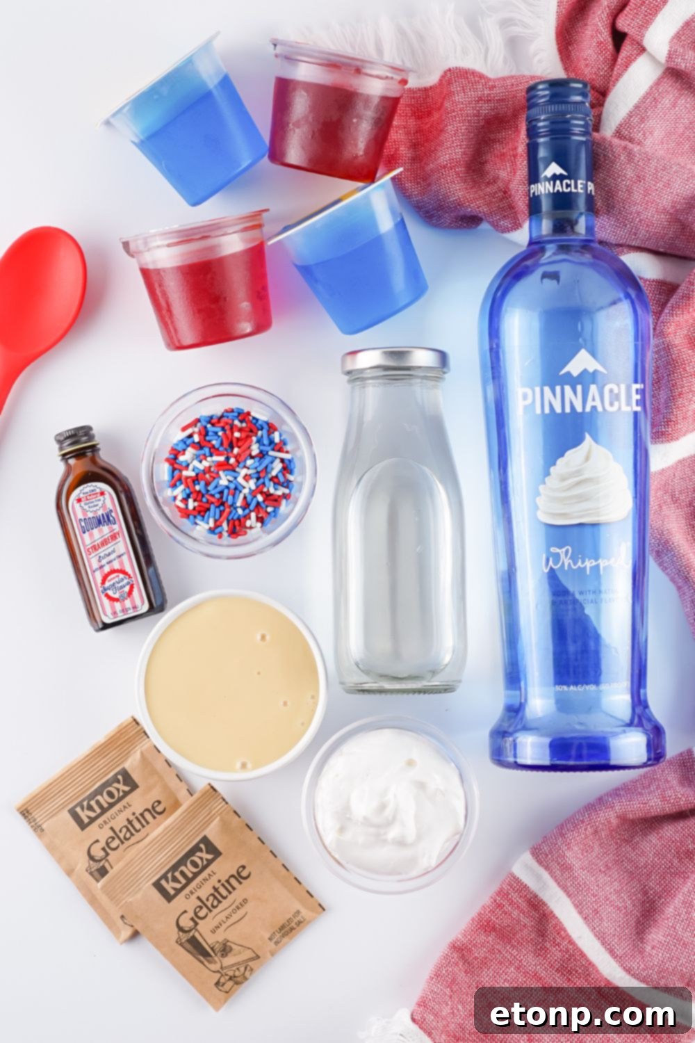 All the essential ingredients for making Red, White, and Blue Stained Glass Jello Shots laid out neatly on a table.