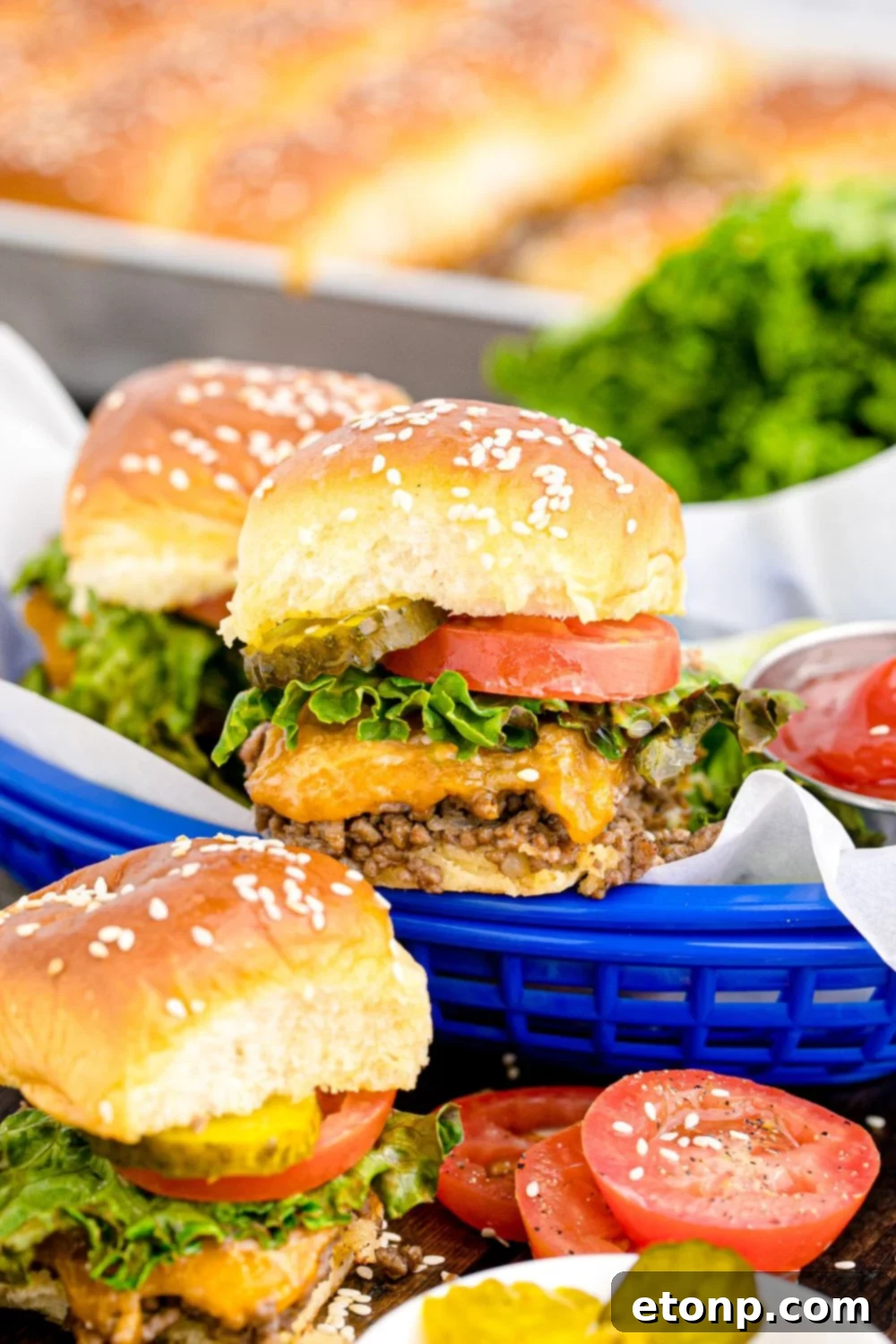 Classic Cheeseburger Sliders in rustic baskets and spread out on a wooden table, garnished with fresh tomatoes, a bowl of pickles, and a small dish of ketchup, creating an inviting party spread.
