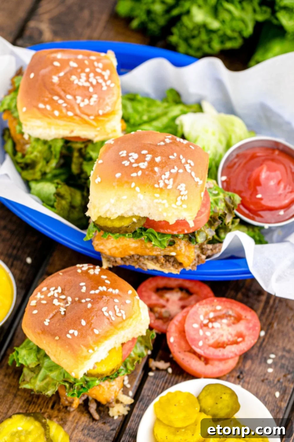 A tempting stack of cheesy beef sliders, generously loaded with various fresh toppings, artfully arranged on a wooden table, with an extra basket of sliders nearby, ready for any gathering.