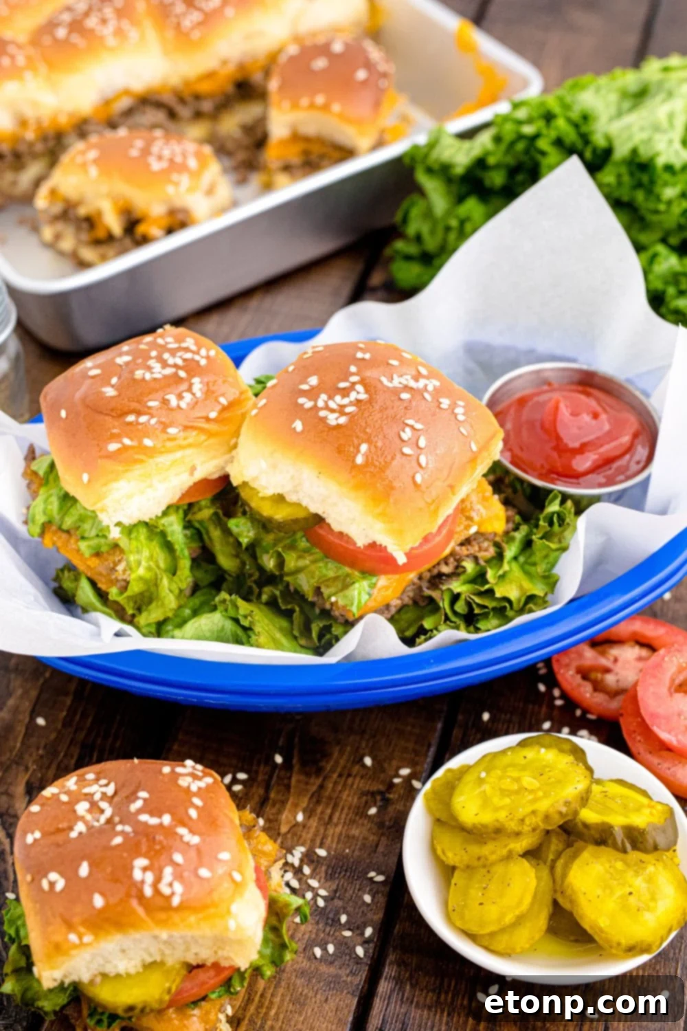 A grand display of Classic Cheeseburger Sliders spread out on a wooden table, showcased in both a baking pan and charming baskets, surrounded by an inviting assortment of condiments and fresh burger toppings.