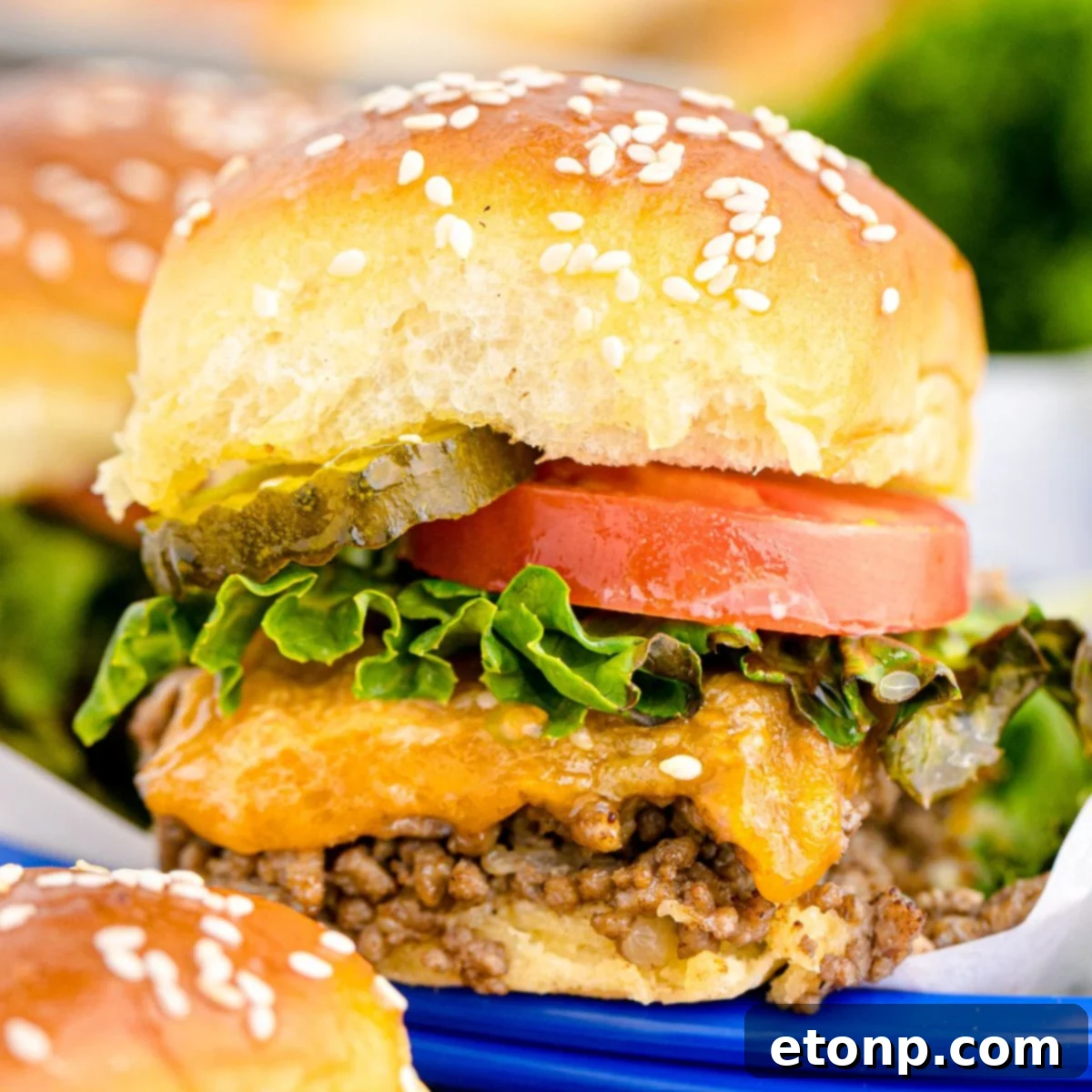 A vibrant blue basket brimming with Classic Cheeseburger Sliders, artfully arranged on a rustic wooden table alongside additional mini burgers, showcasing their appealing golden-brown buns and melted cheese.
