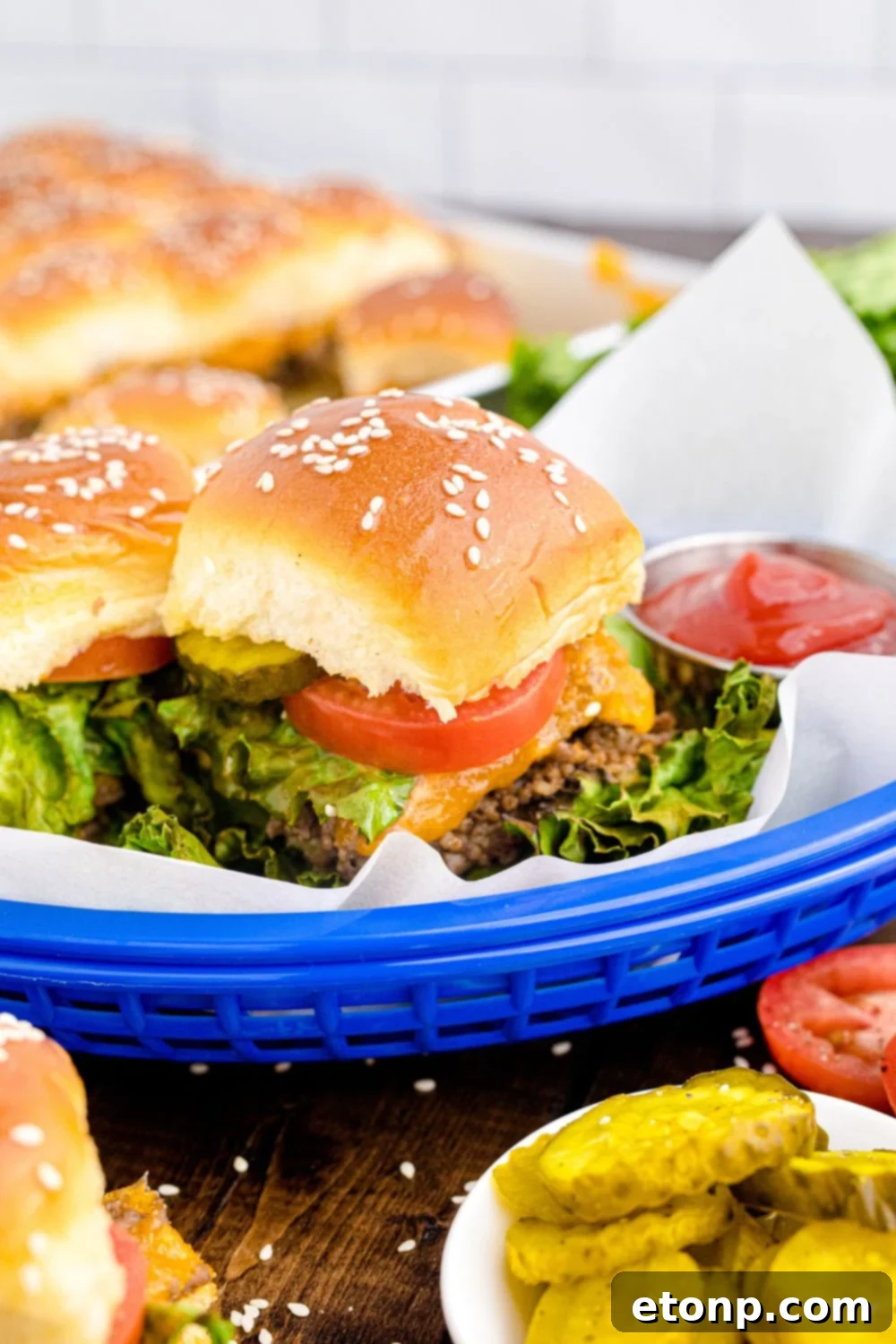 Classic Cheeseburger Sliders presented in charming blue baskets on a wooden table, surrounded by various condiments and burger toppings, creating an inviting and customizable spread for guests.