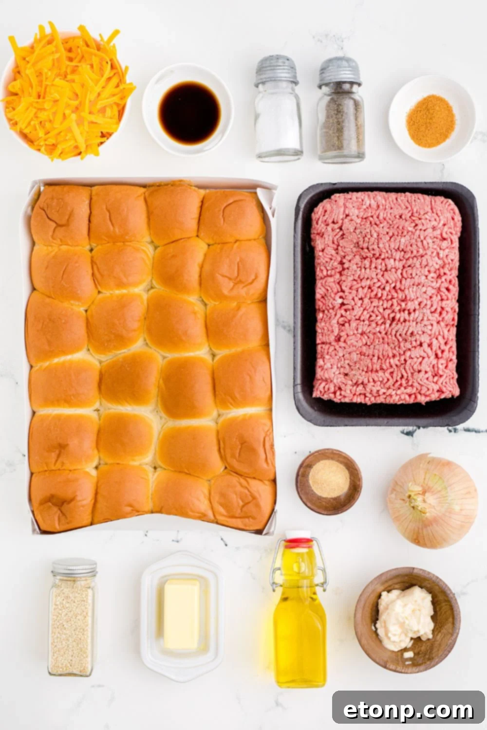 All the essential ingredients for Classic Cheeseburger Sliders meticulously spread out on a clean white table, ready for preparation, highlighting fresh produce and seasonings.