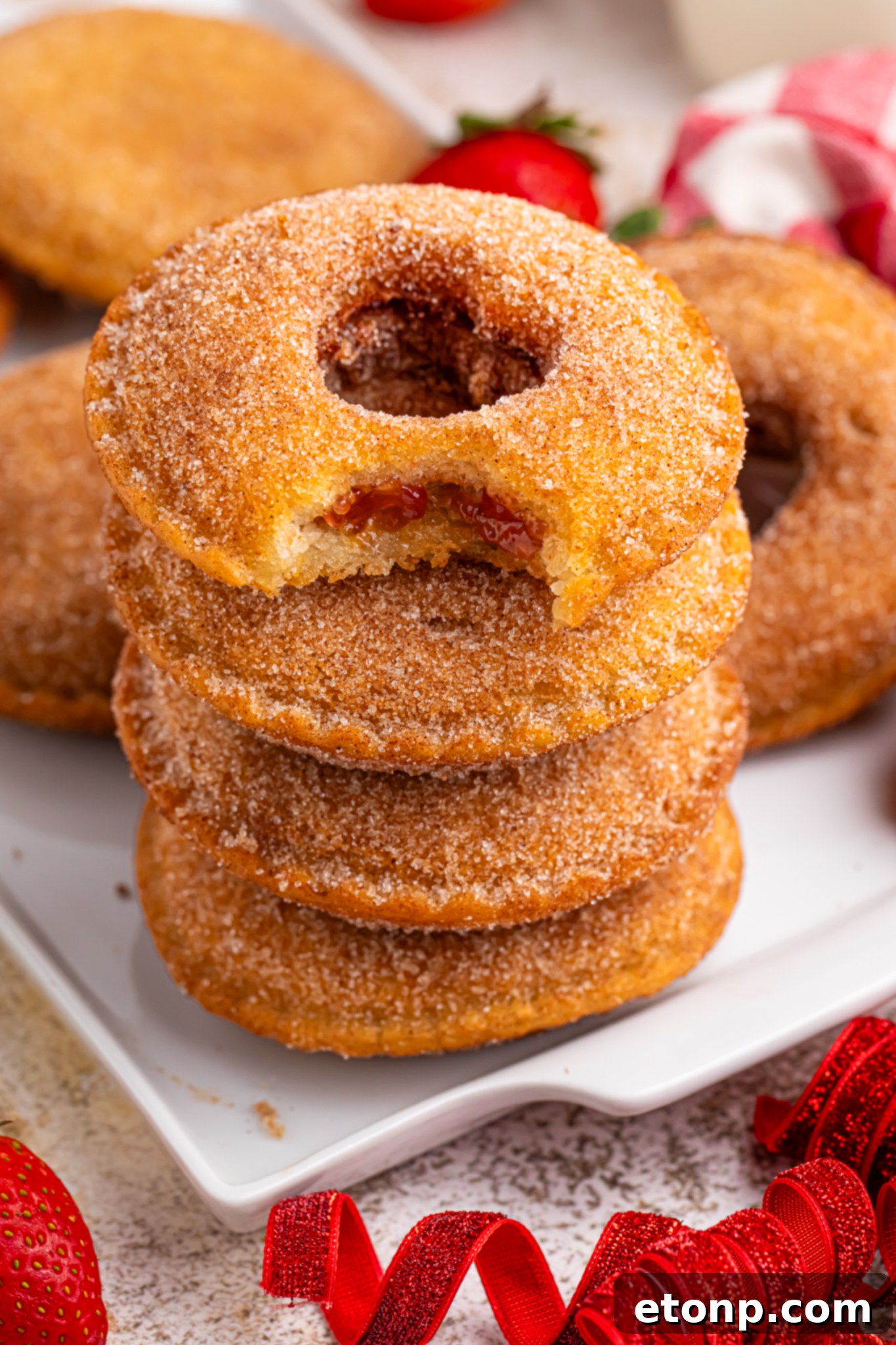 TikTok Fried Strawberry Uncrustables 2 Plate of golden-fried strawberry Uncrustables coated in cinnamon sugar, garnished with fresh strawberries