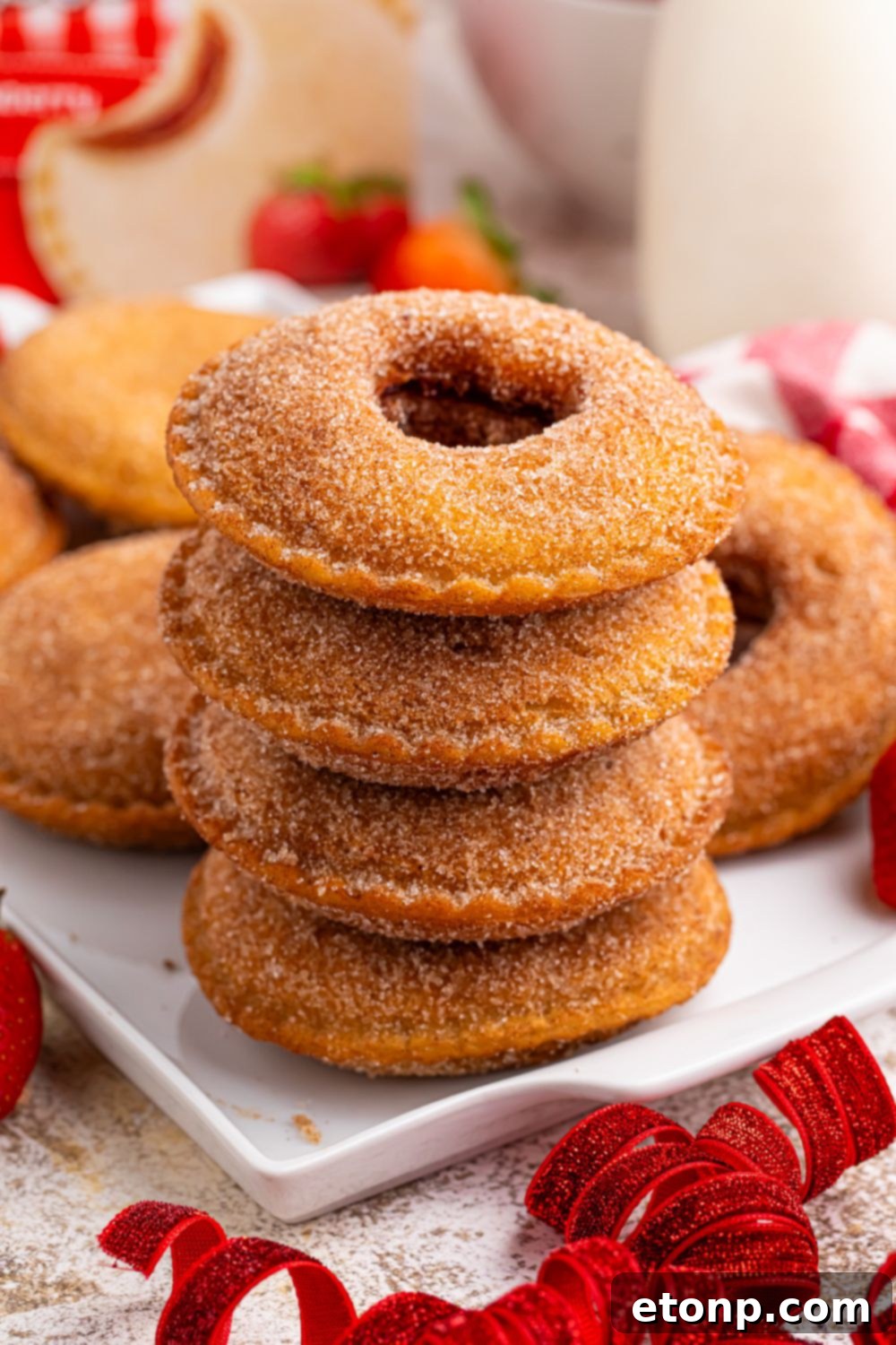 TikTok Fried Strawberry Uncrustables 16 Fried strawberry Uncrustables stacked on a plate, with more spread out on a tray behind, ready to be served