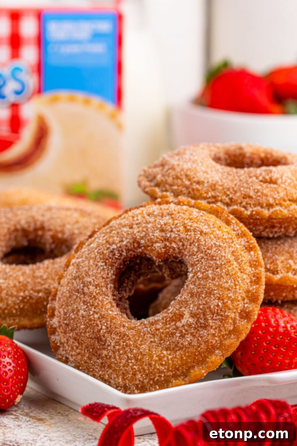 TikTok Fried Strawberry Uncrustables 19 Close-up of fried strawberry Uncrustables on a table with heart cutouts, with a box of Uncrustables in the background