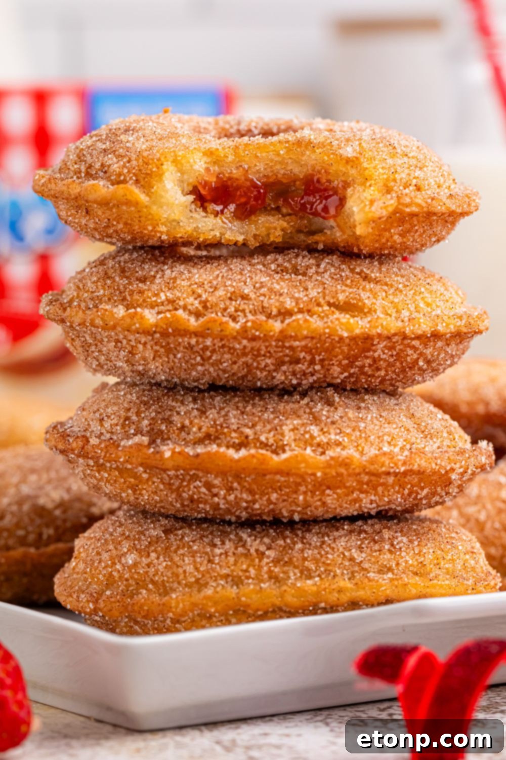TikTok Fried Strawberry Uncrustables 6 Close-up of a stack of fried strawberry Uncrustables, with one on top having a bite taken out of it, revealing the soft filling