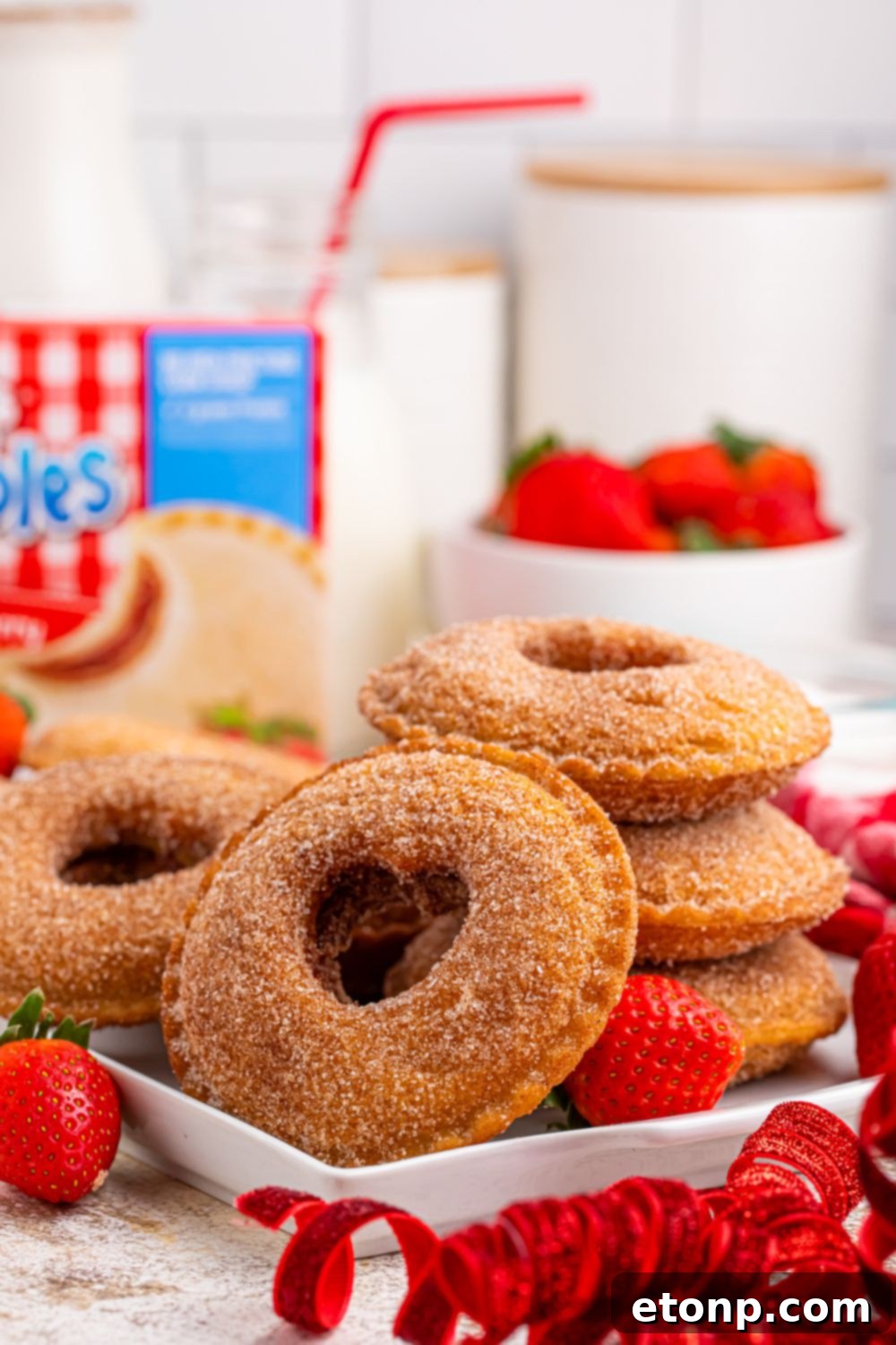TikTok Fried Strawberry Uncrustables 7 Arrangement of fried strawberry Uncrustables on a plate and around a bowl of fresh strawberries, with a glass of milk