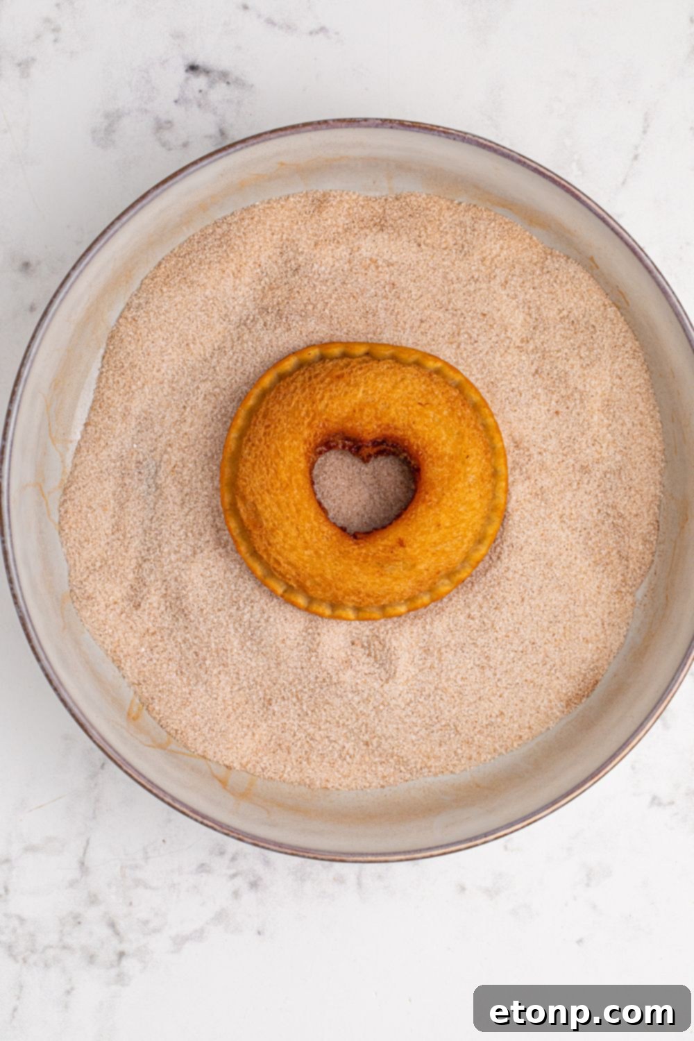 TikTok Fried Strawberry Uncrustables 9 Close-up of a fried Uncrustable being dipped and coated in a bowl of cinnamon sugar mixture