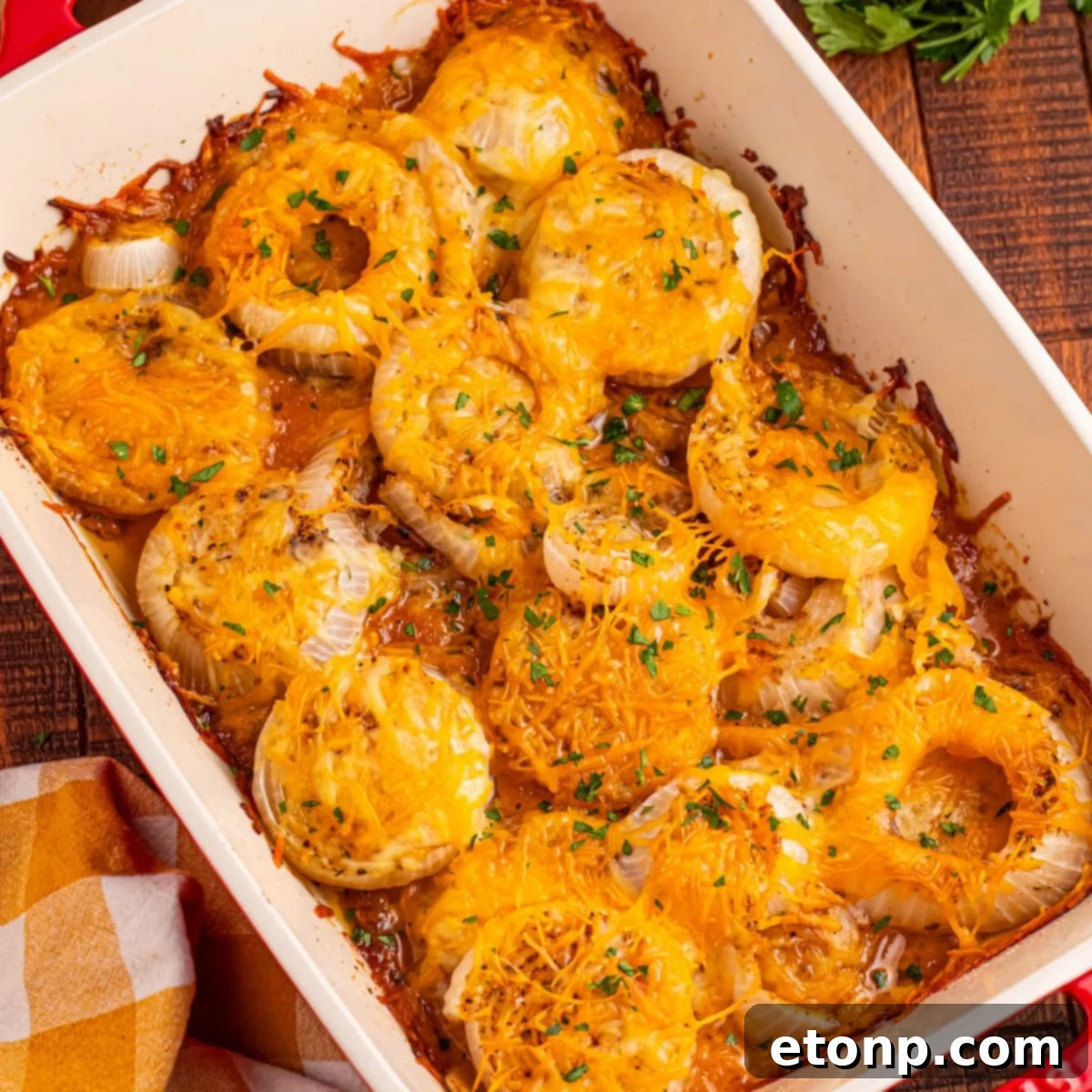 Cheesy Tennessee Onion Bake 2 Cheesy Tennessee Onions in a casserole pan on a rustic wooden table, garnished with fresh herbs.