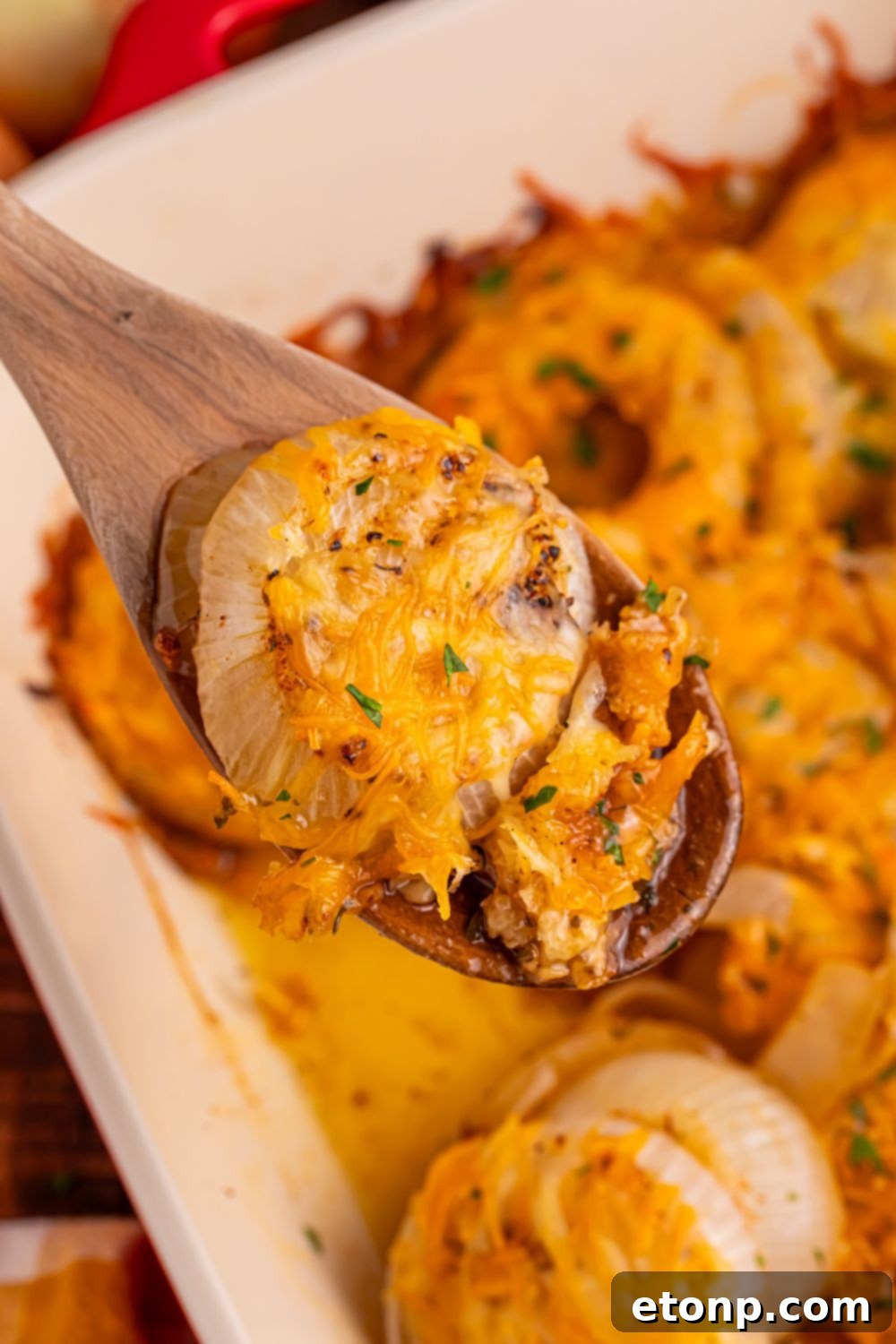 Cheesy Tennessee Onion Bake 16 A wooden spoon with a delectable portion of baked cheesy onions, ready to be enjoyed.