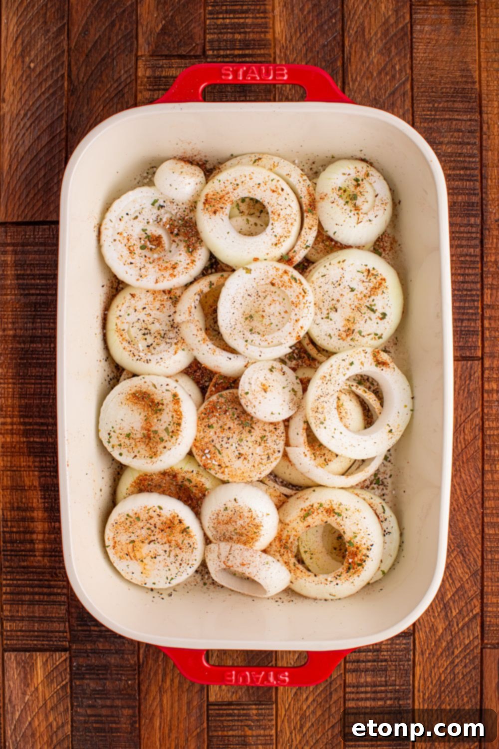 Cheesy Tennessee Onion Bake 8 Sliced sweet onions seasoned and layered in a casserole dish before baking.