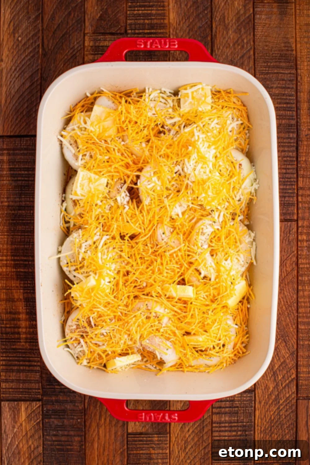 Cheesy Tennessee Onion Bake 9 Layers of sliced onions topped with a generous sprinkle of cheese, ready for the oven.