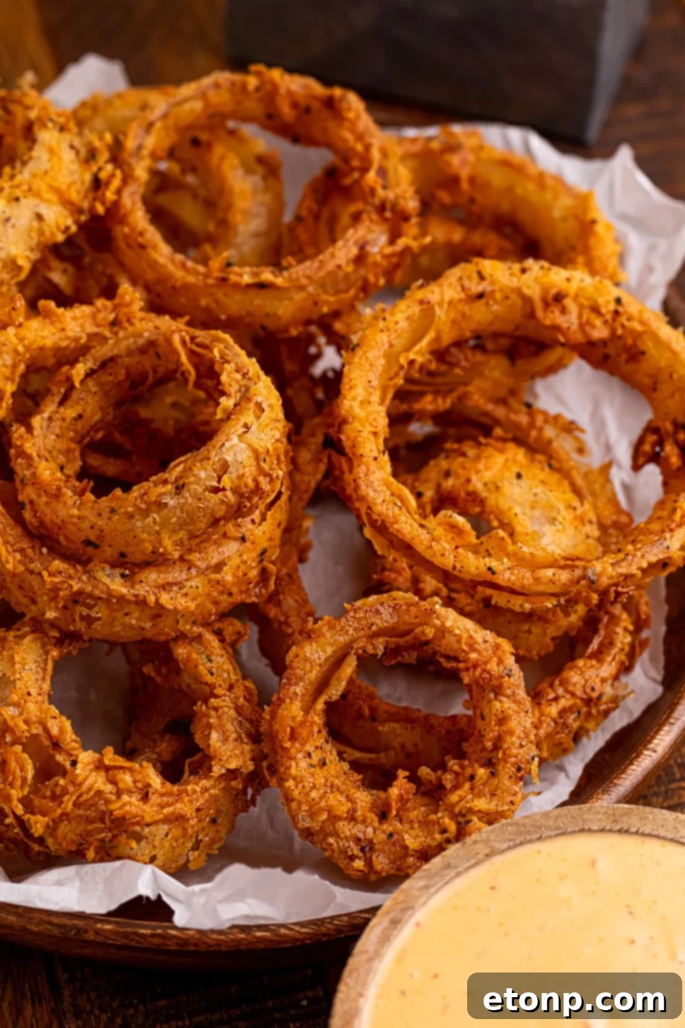 Golden Crispy Homemade Onion Rings 17 Homemade Deep Fried Onion Rings in a bowl with a bowl of dip to the side