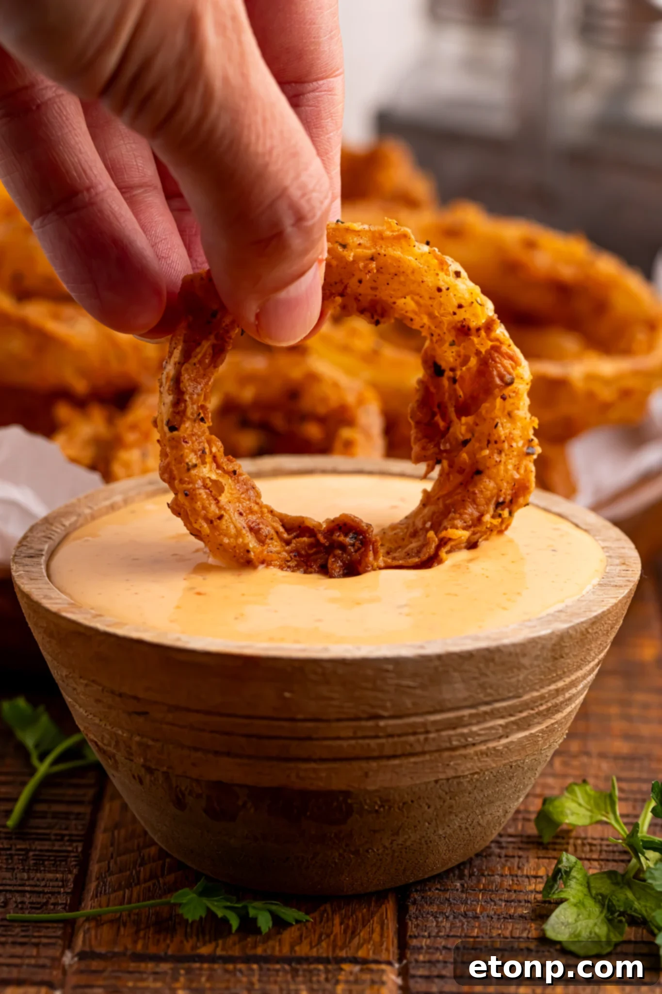 Golden Crispy Homemade Onion Rings 18 a Hand dipping a onion ring in sauce
