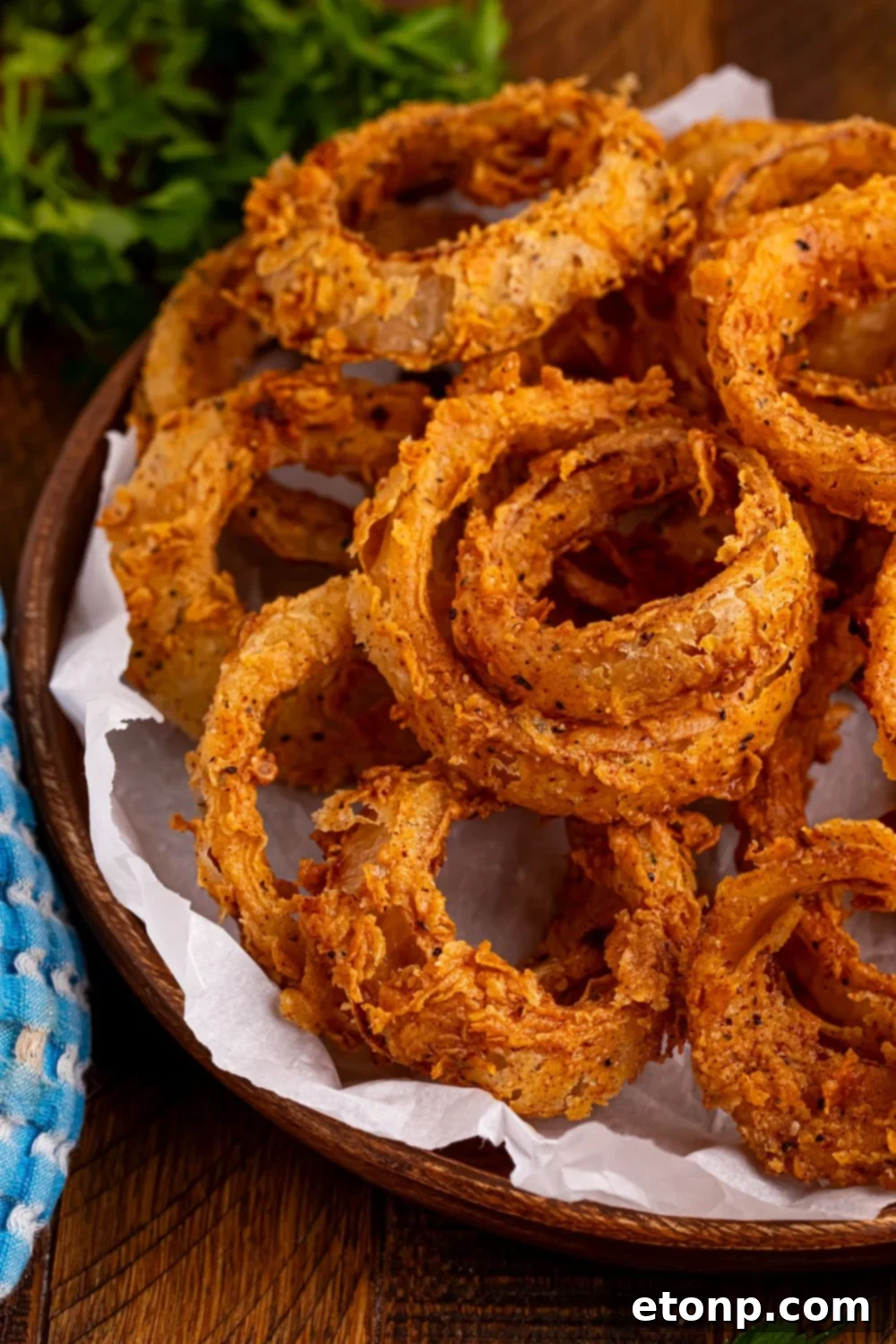 Golden Crispy Homemade Onion Rings 4 Homemade Deep Fried Onion Rings in a tray with some parchment paper and some parsley behind it