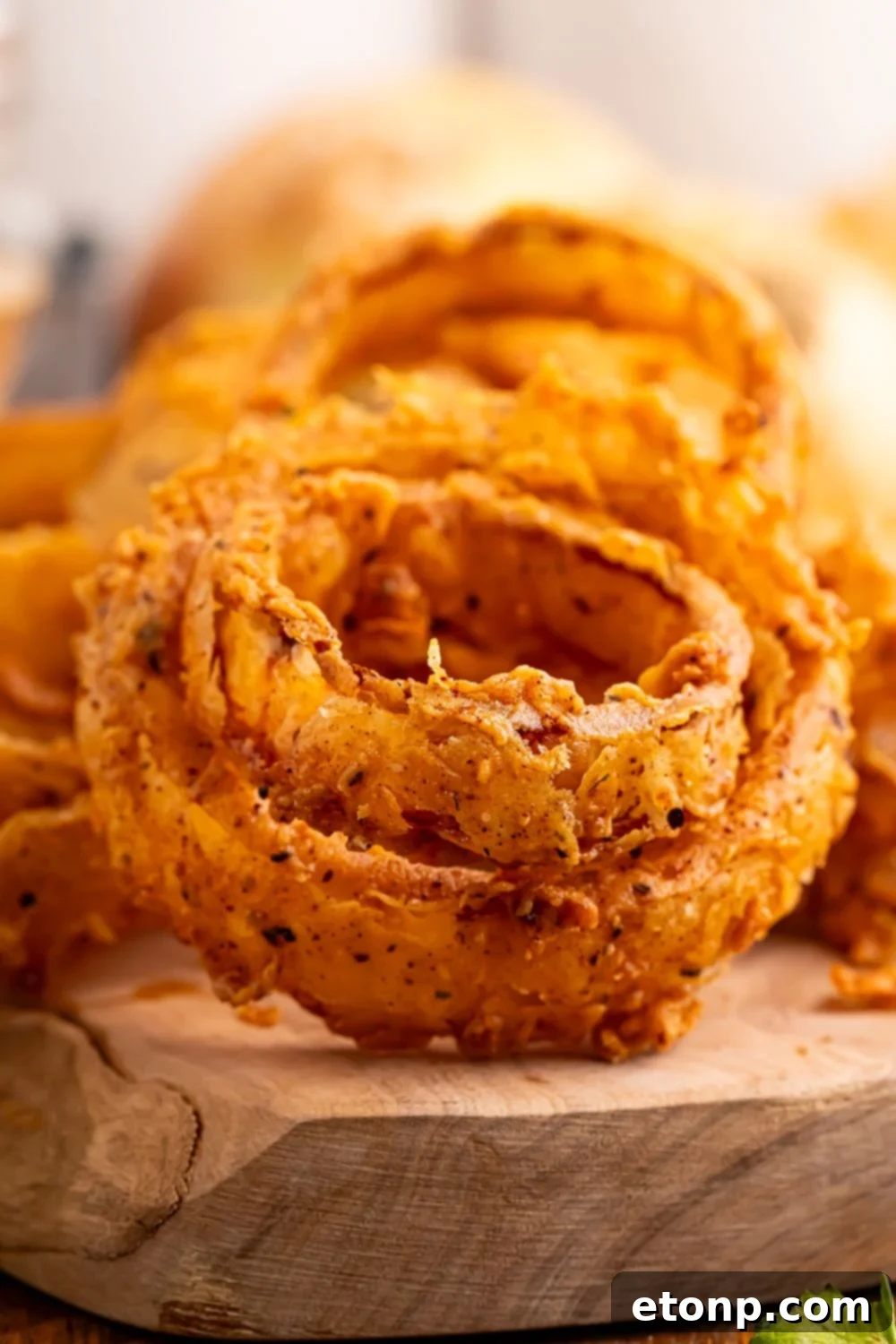 Golden Crispy Homemade Onion Rings 5 onion rings stacked together on a wooden tray on table
