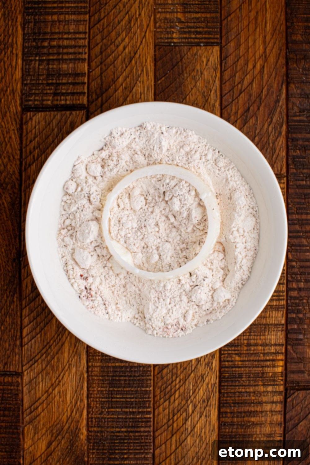 Golden Crispy Homemade Onion Rings 9 flour mixture in a bowl with onion on top of flour
