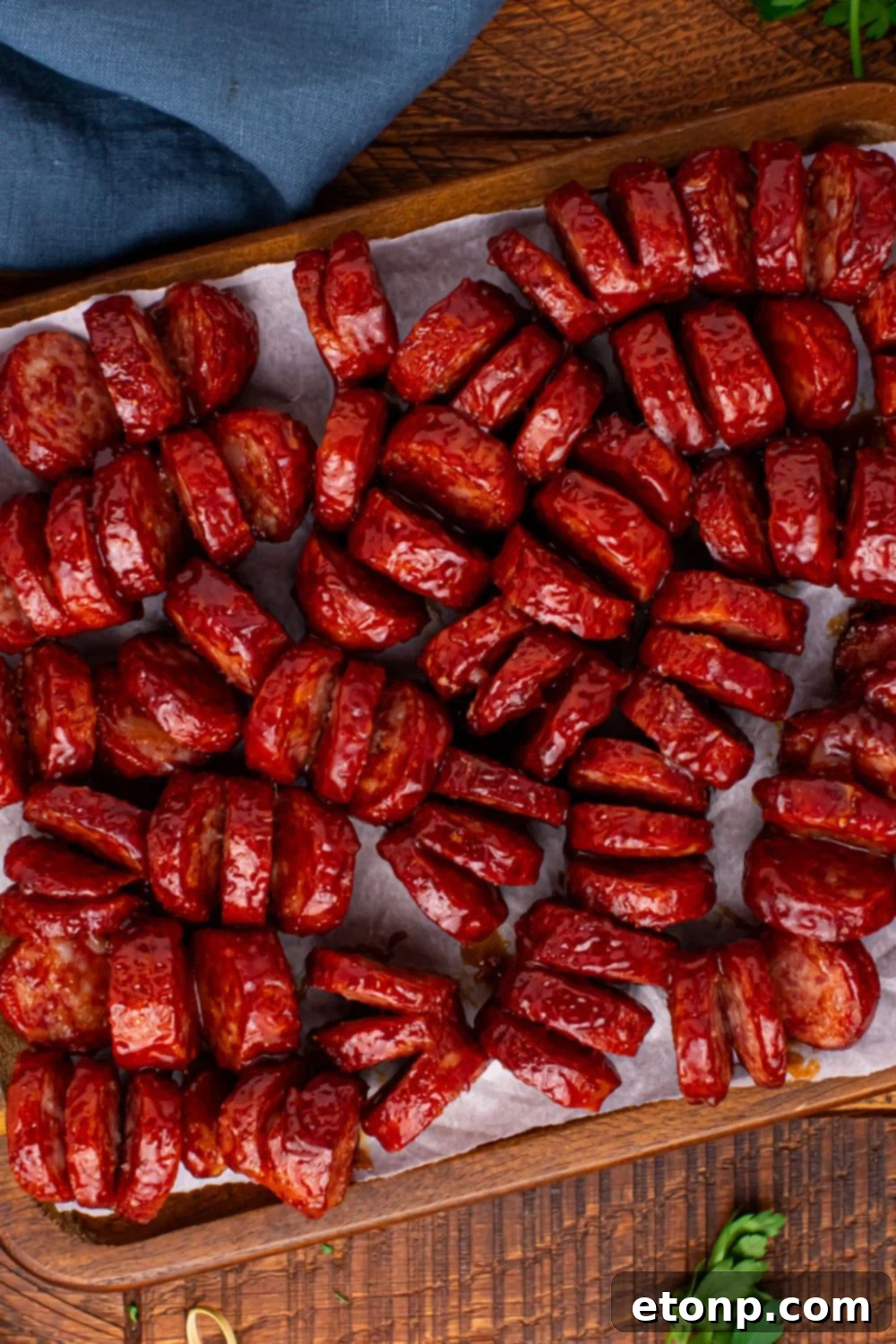 BBQ Hasselback Smoked Sausages on a tray with a blue towel to the side 