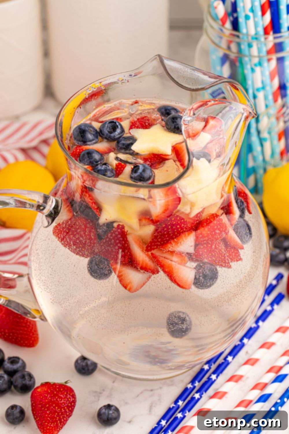 Liberty Lemon Sparkle 12 Patriotic Sparkling Lemonade in a pitcher on table with more red white and blue items to showcase the colors