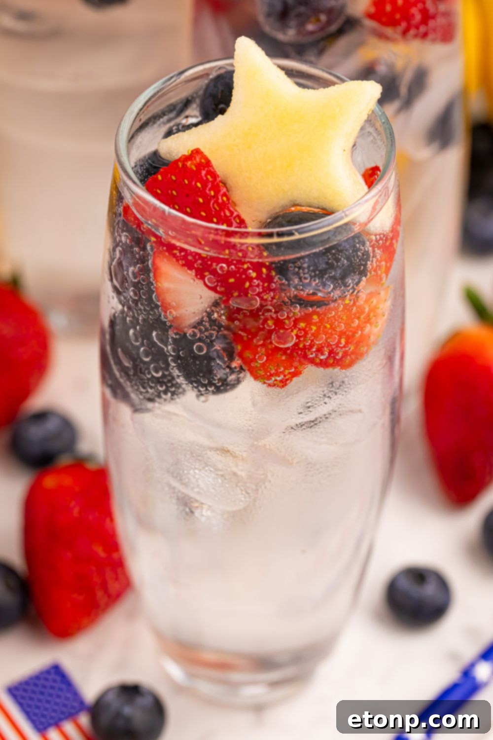 Liberty Lemon Sparkle 13 glass full of Patriotic Sparkling Lemonade and topped with fruit sitting on table