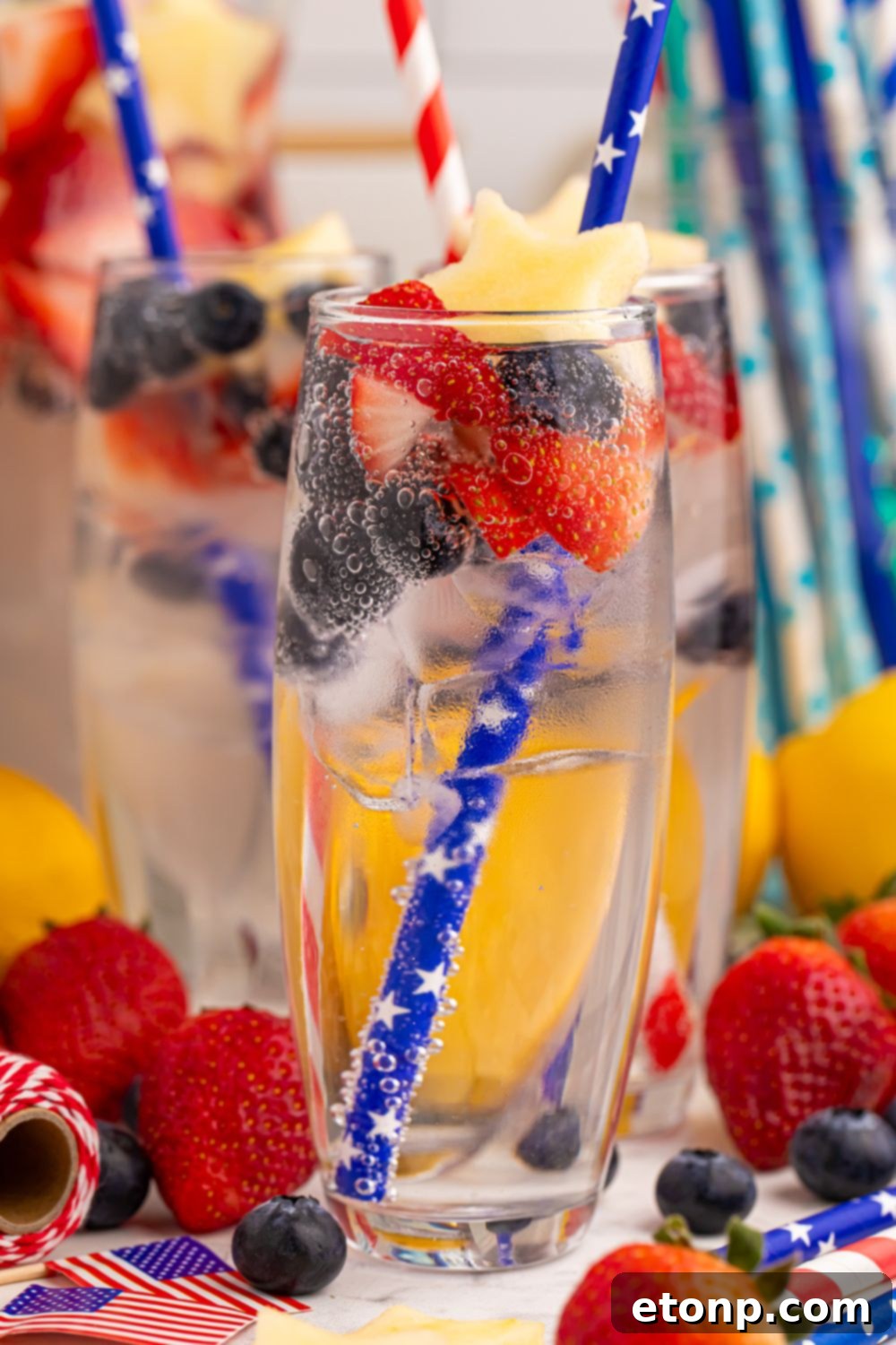 Liberty Lemon Sparkle 16 table with Fourth of July drinks with straws and fresh berries and apples in each glass