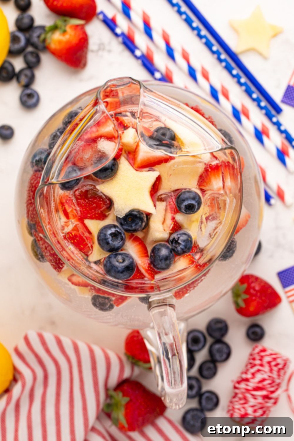 Liberty Lemon Sparkle 17 glass pitcher with Patriotic Sparkling Lemonade in it, and topped with star shaped apples, blueberries and strawberries