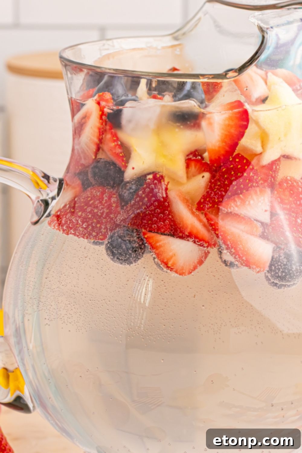 Liberty Lemon Sparkle 22 close up view of Patriotic Sparkling Lemonade in pitcher, with a mix of fruit on top of pitcher to add color