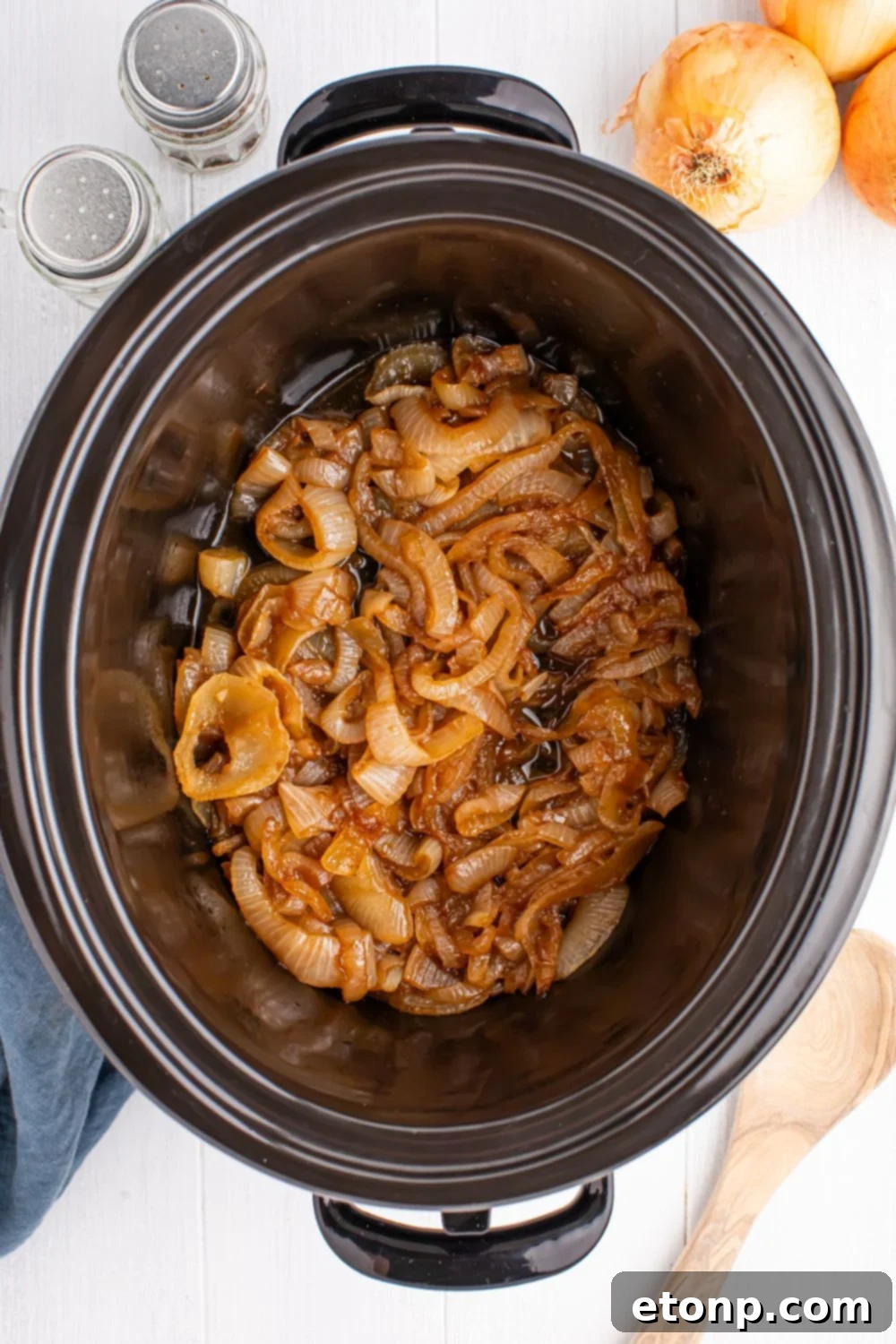 overhead look of CrockPot Caramelized onions on table with onions and salt and pepper to side 