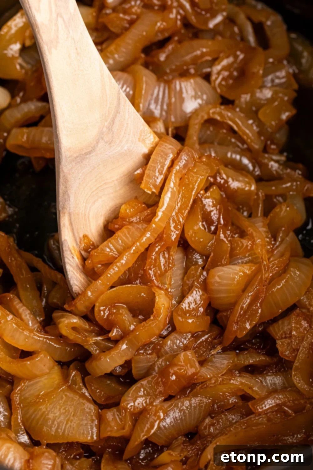 CrockPot Caramelized onions being stirred with a wooden spoon