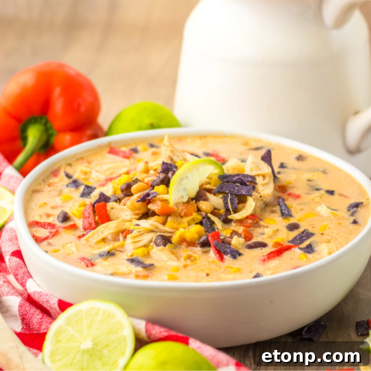Side view of Slow Cooker Tortilla Soup in a white bowl with a white and red checkered napkin.