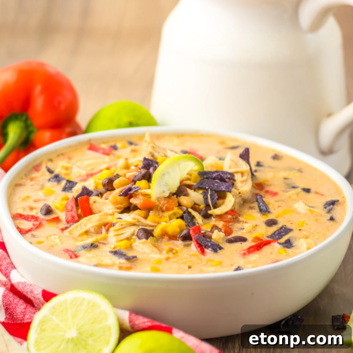 Close up side view of Slow Cooker Tortilla Soup in a white bowl with a tortilla chip topping. 