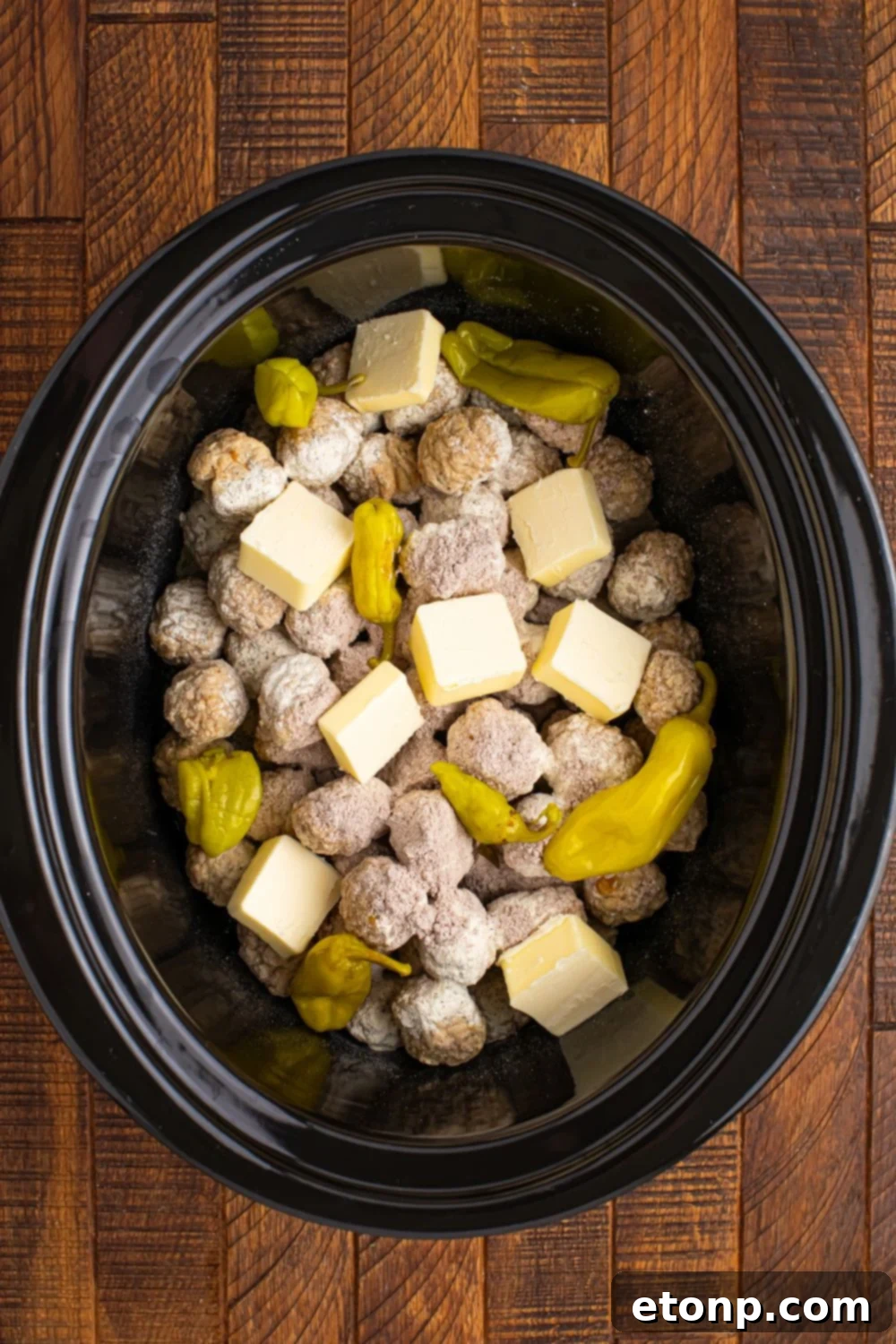 5 Ingredient Crockpot Mississippi Meatballs 11 frozen meatballs in a CrockPot with butter and peppers on top