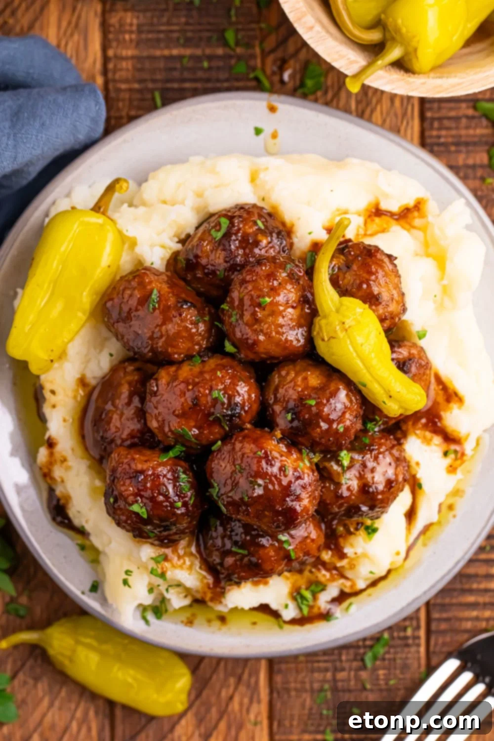 5 Ingredient Crockpot Mississippi Meatballs 15 Crockpot Mississippi Meatballs on a plate with mashed potatoes underneath a fork to the side on table