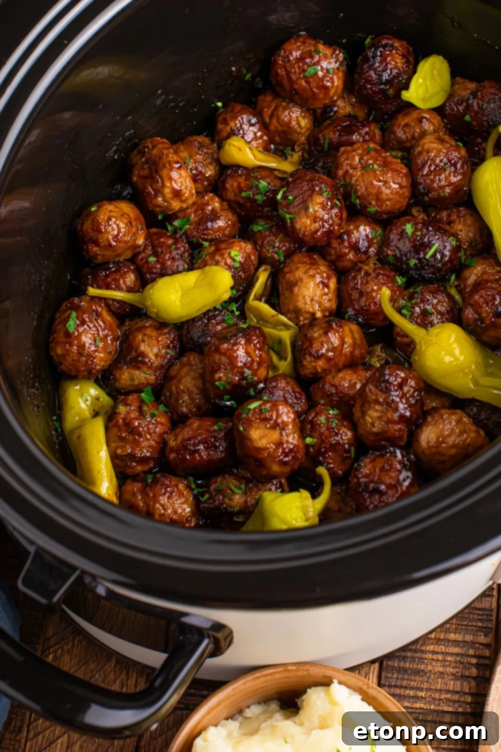 5 Ingredient Crockpot Mississippi Meatballs 18 CrockPot angled to side on table with Mississippi meatballs inside and peppers